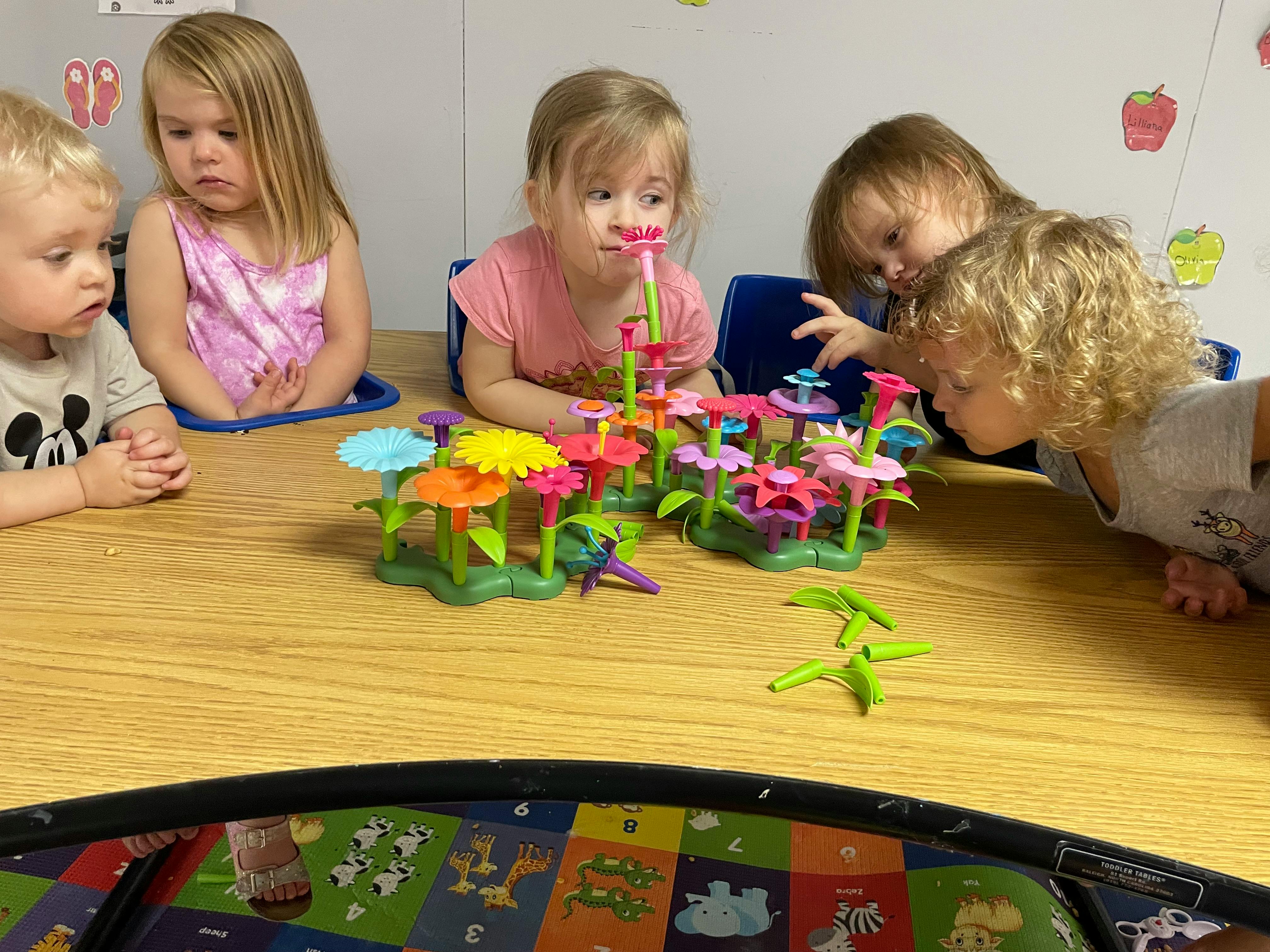 Four children playing with flower-shaped toys on a table
