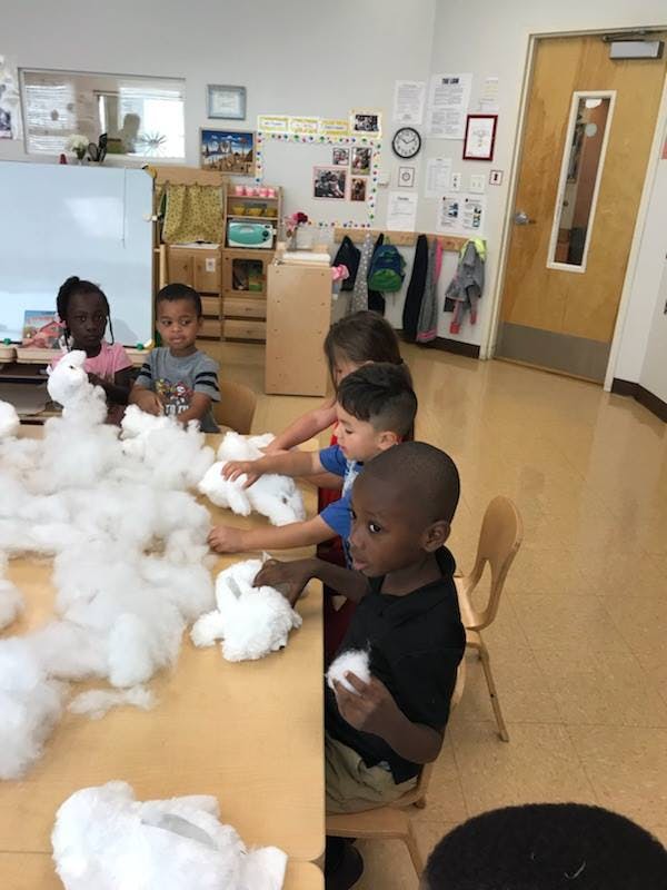 Children at a table playing with white fluffy material
