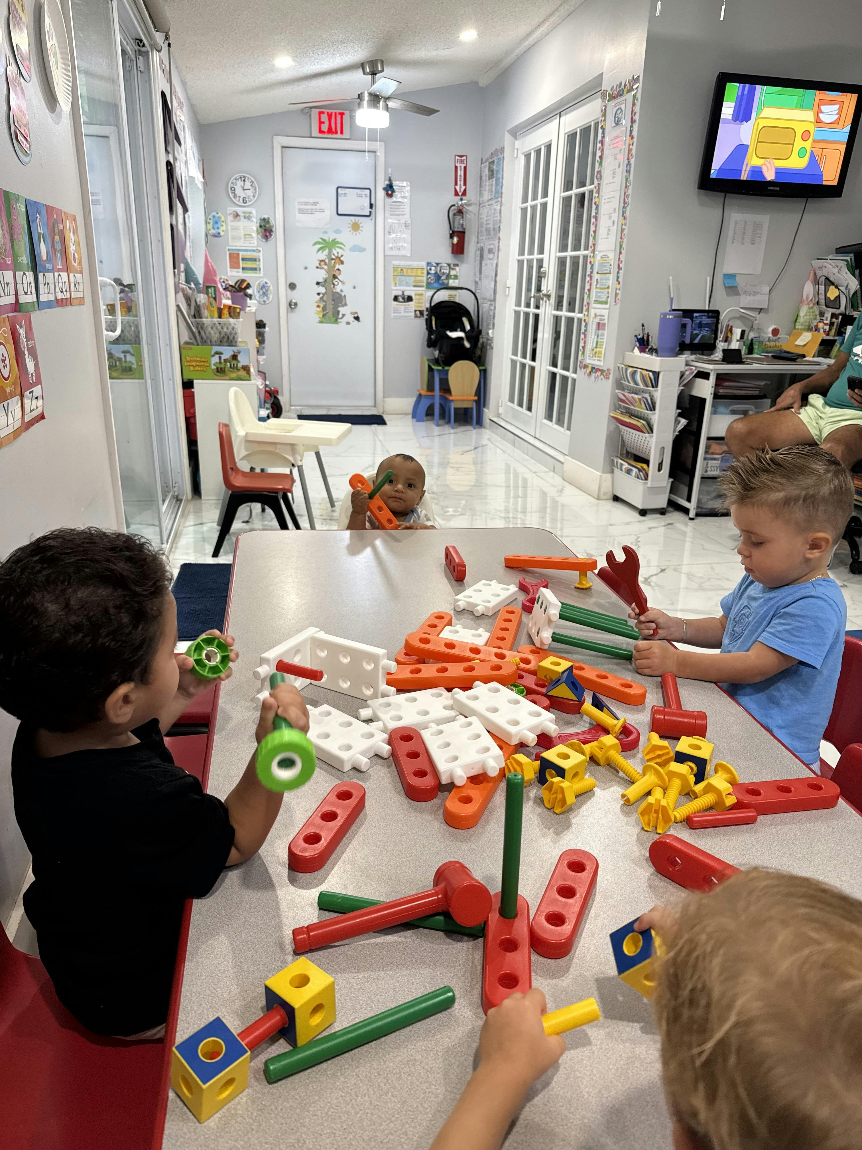 Children playing with colorful plastic building blocks at a table