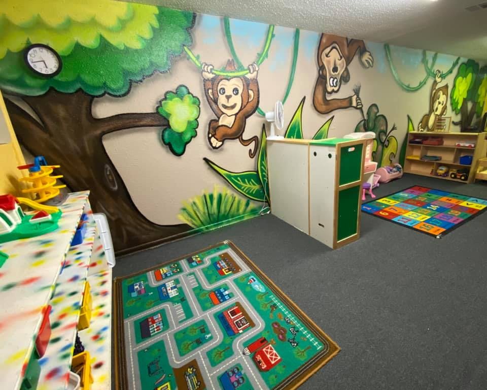 Playroom with jungle mural, toy car rug, and colorful mat