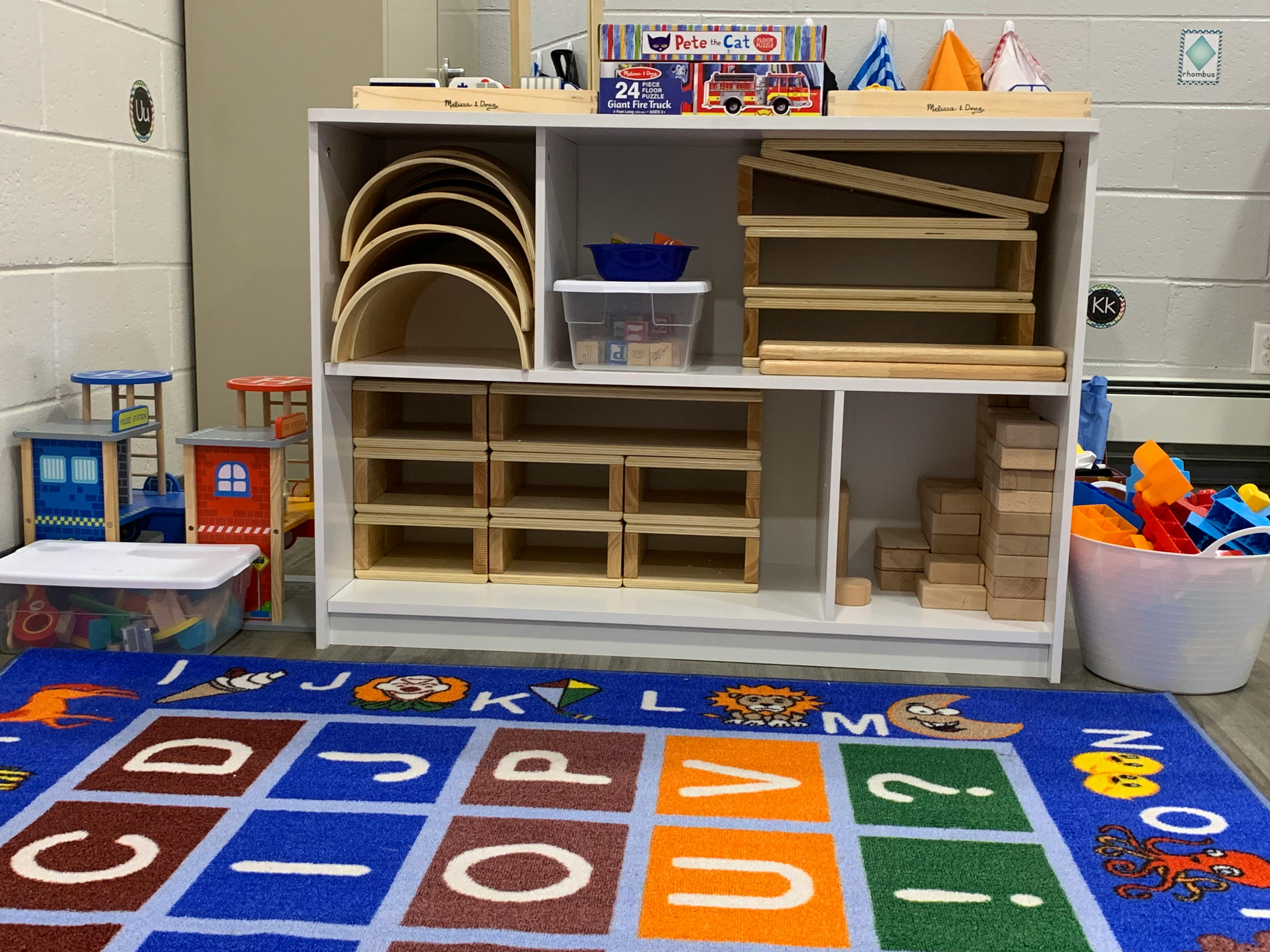 Classroom with an alphabet rug and shelves of wooden toys