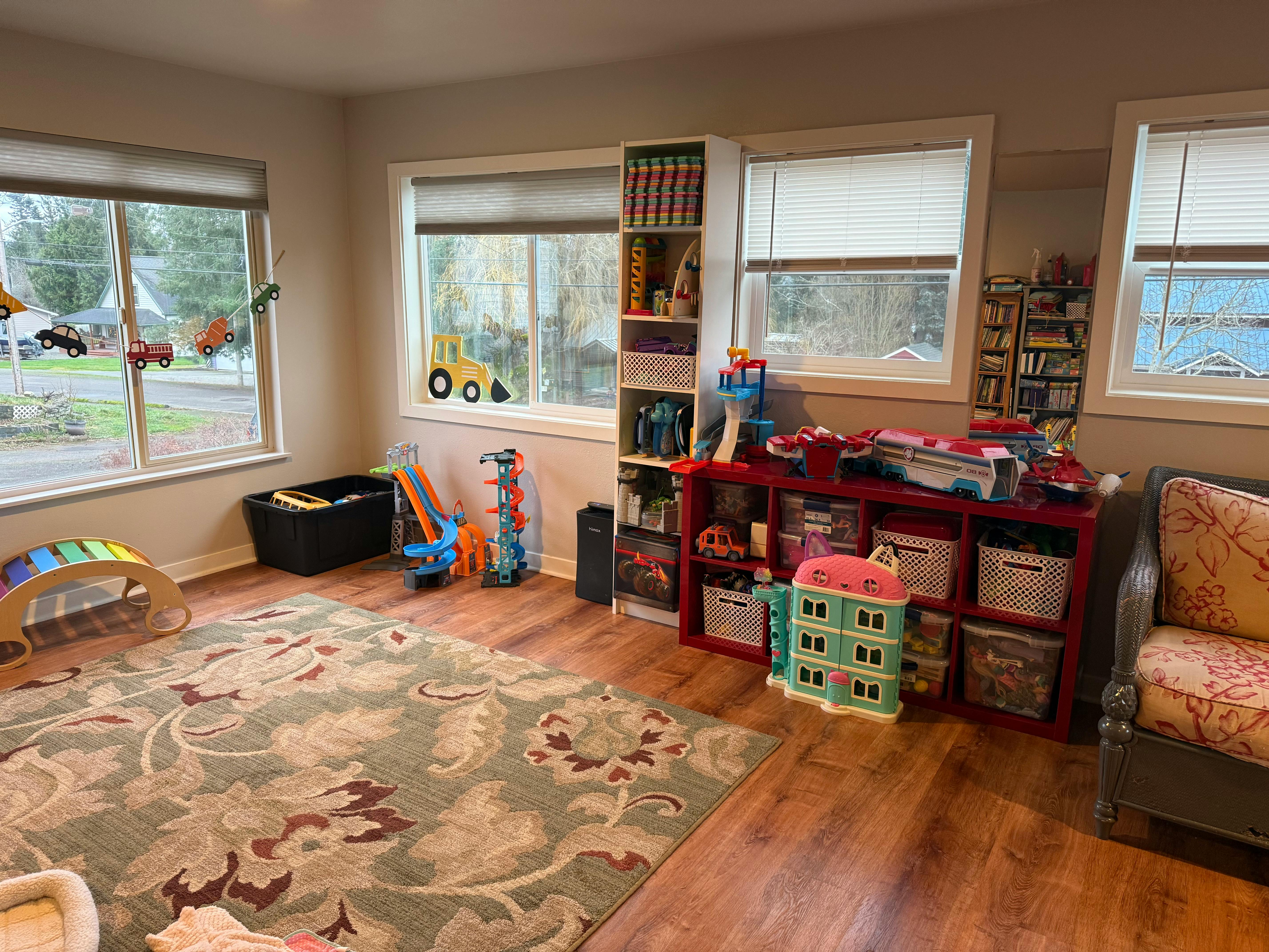 Playroom with toys, shelves, and a patterned rug on a wooden floor