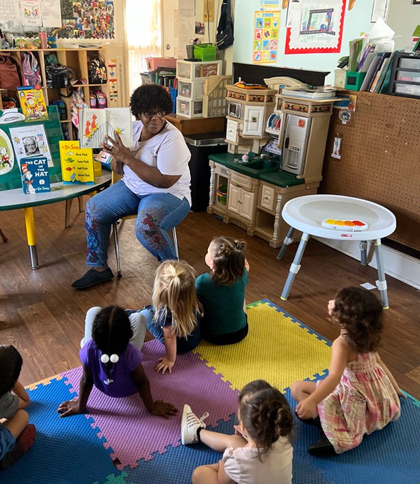 Person reading a book to multiple children in a classroom