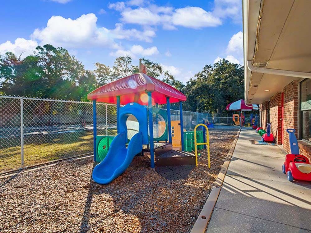 A children's playground with a blue slide on wood chips