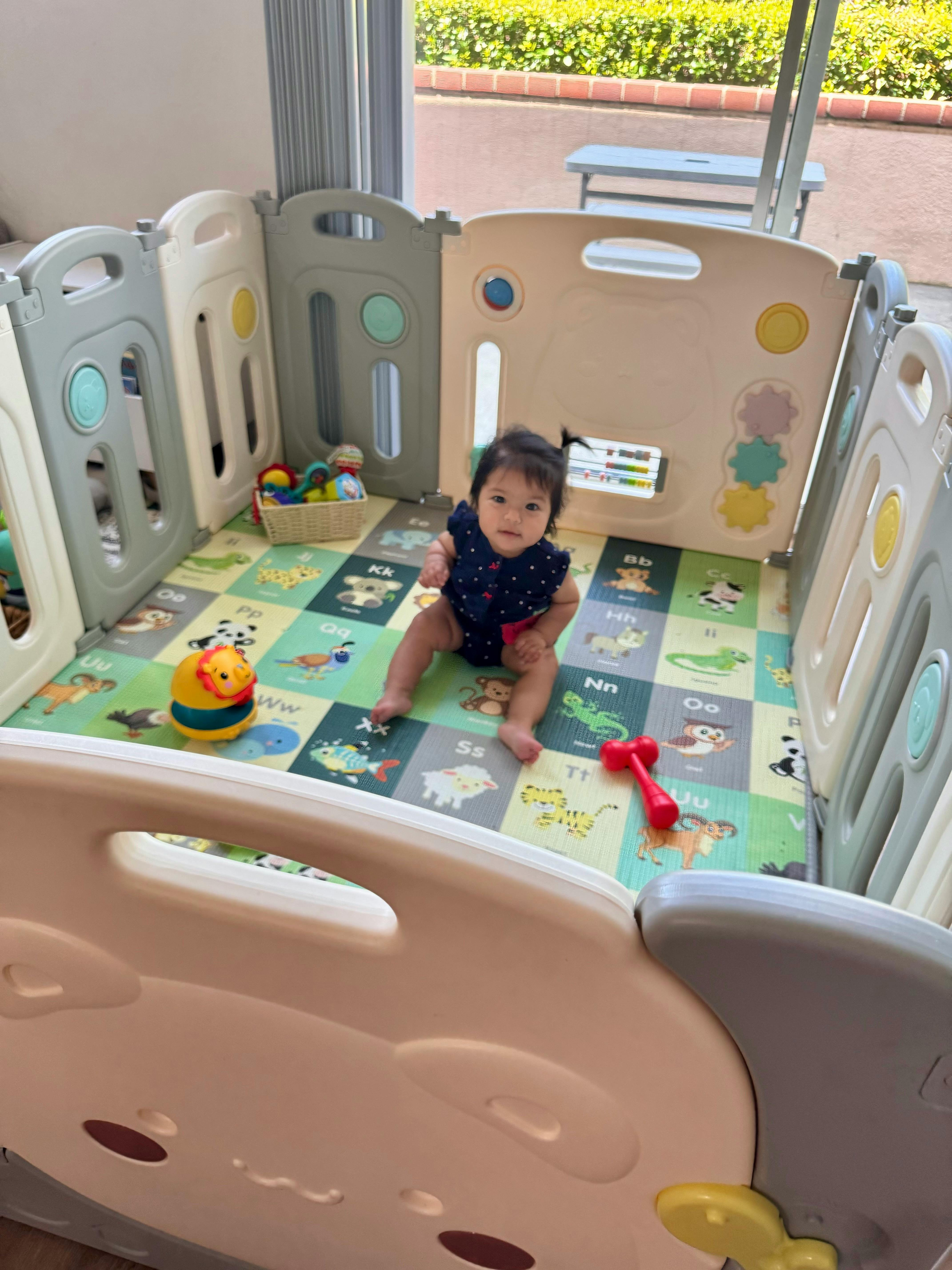Child sitting in a playpen with toys