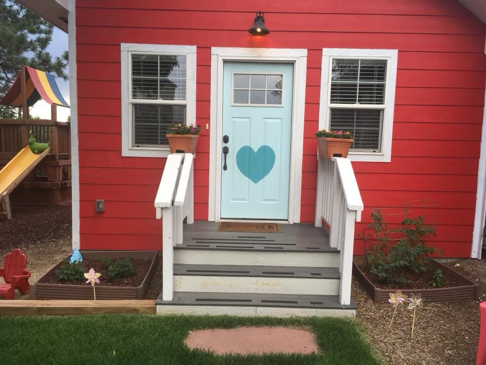 Red house with a light blue door and a heart on it