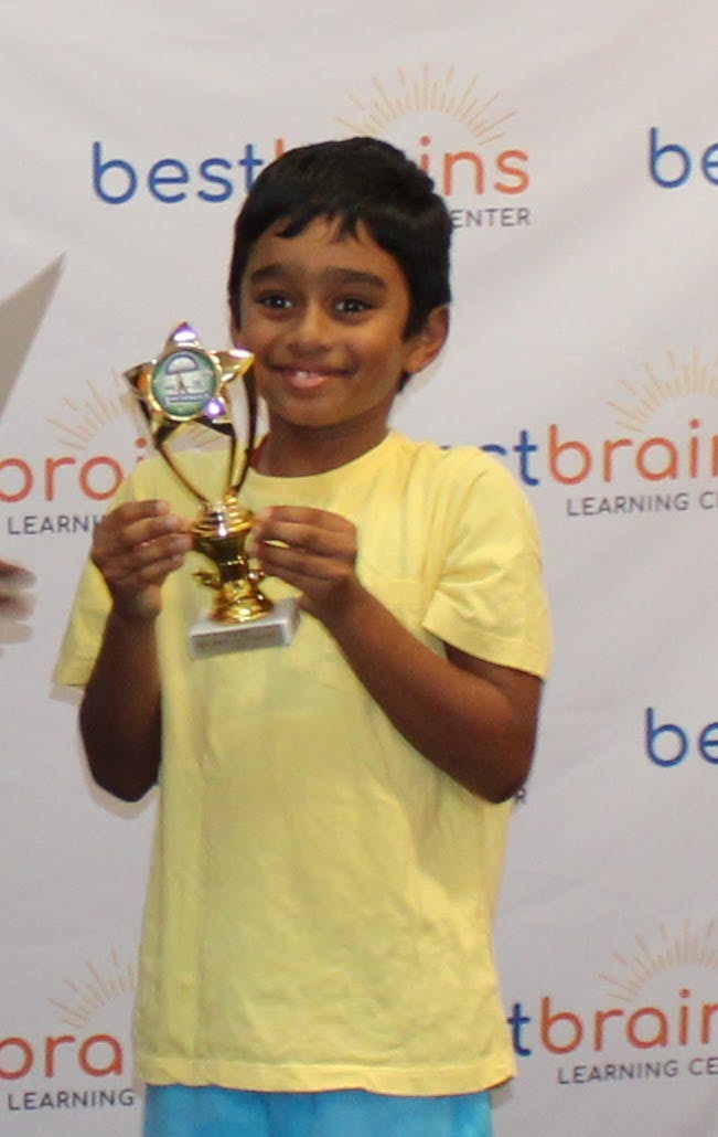 Child in yellow shirt holding a star-shaped trophy