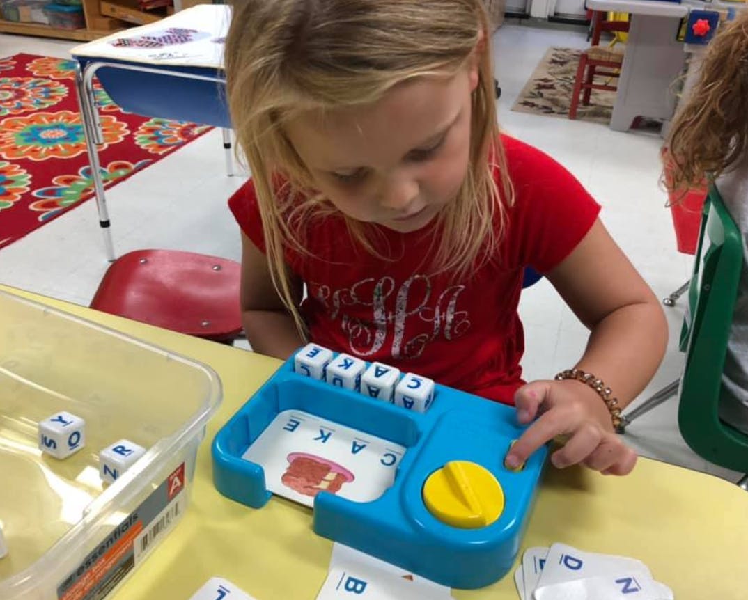 Child playing with a word-building toy in a classroom