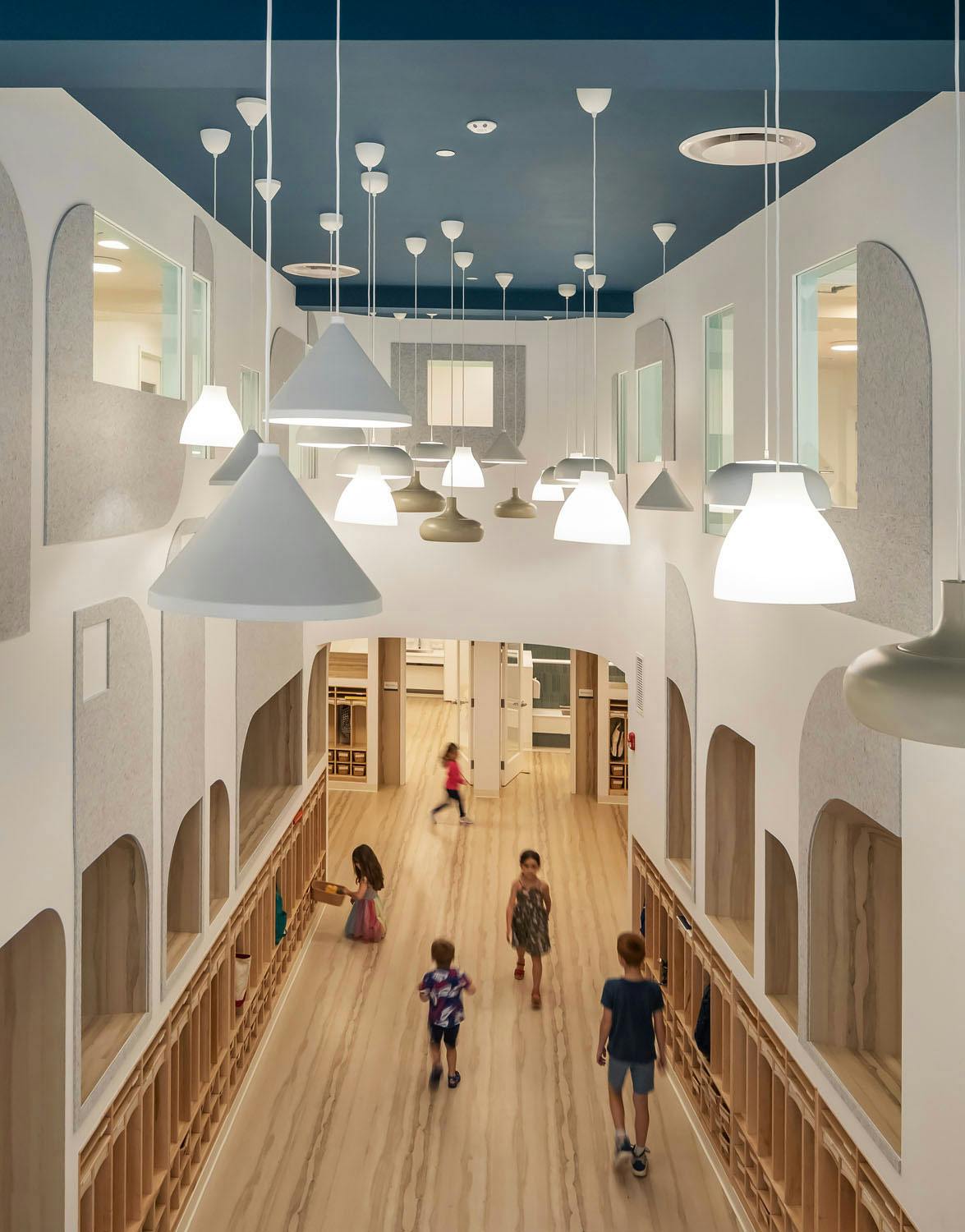 Children walking in a hallway with hanging lights