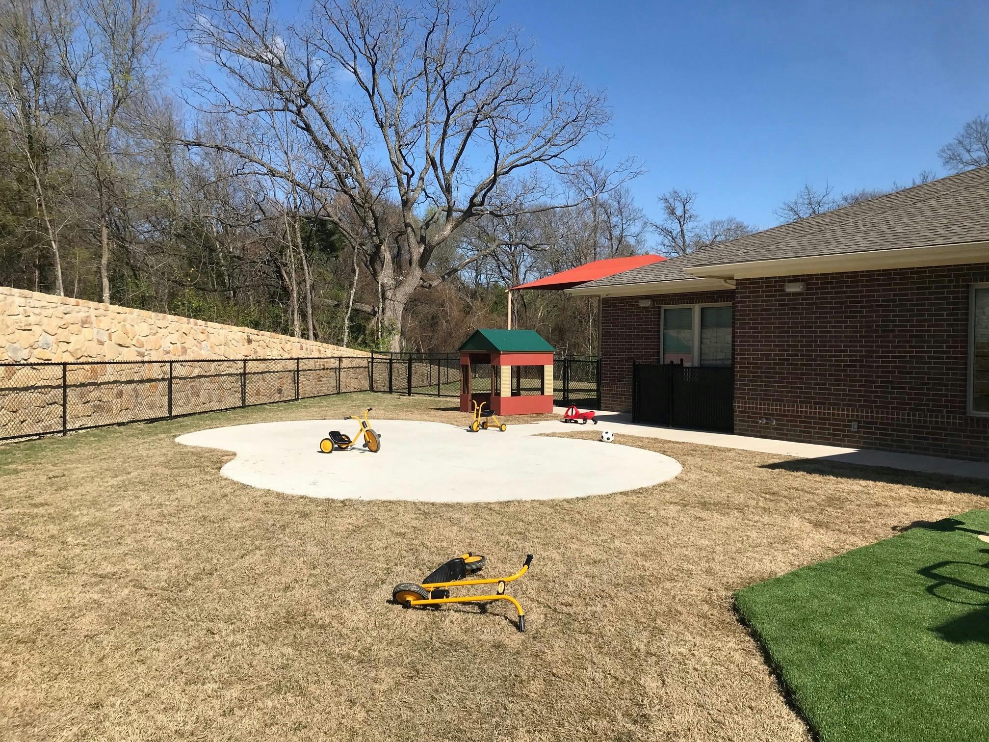 Outdoor play area with a sandbox, playhouse, and building