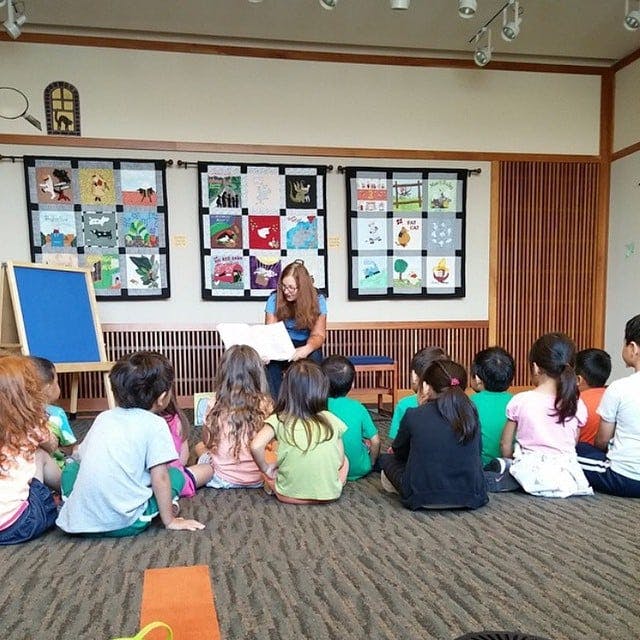 Adult reading to a group of children sitting on the floor