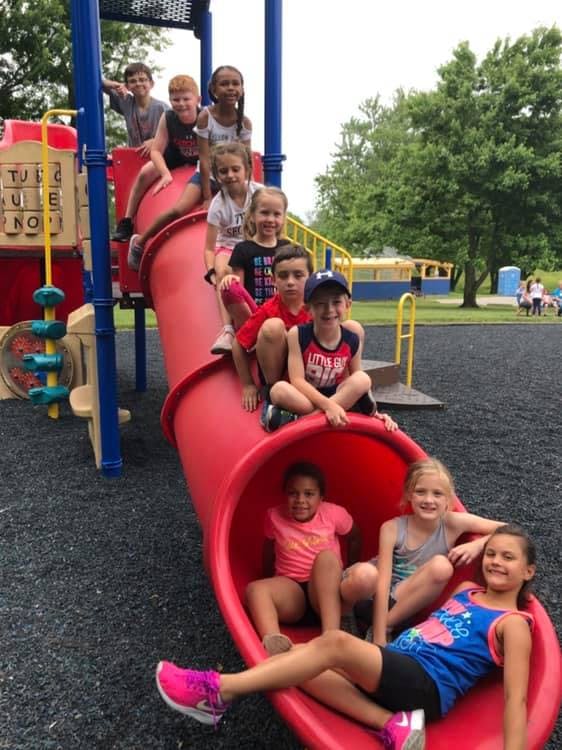 Children sitting on a red playground slide