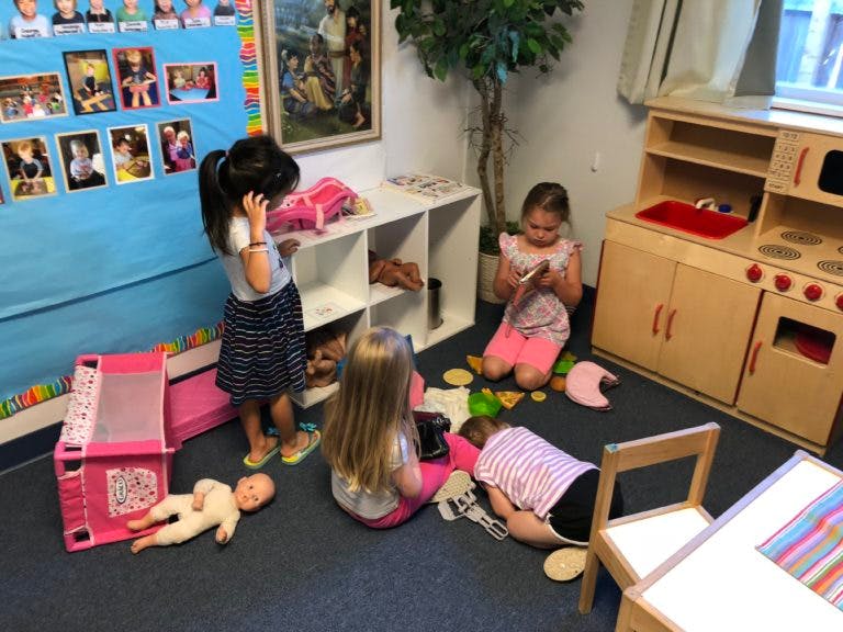 Children playing on the floor in a room with toys and a play kitchen