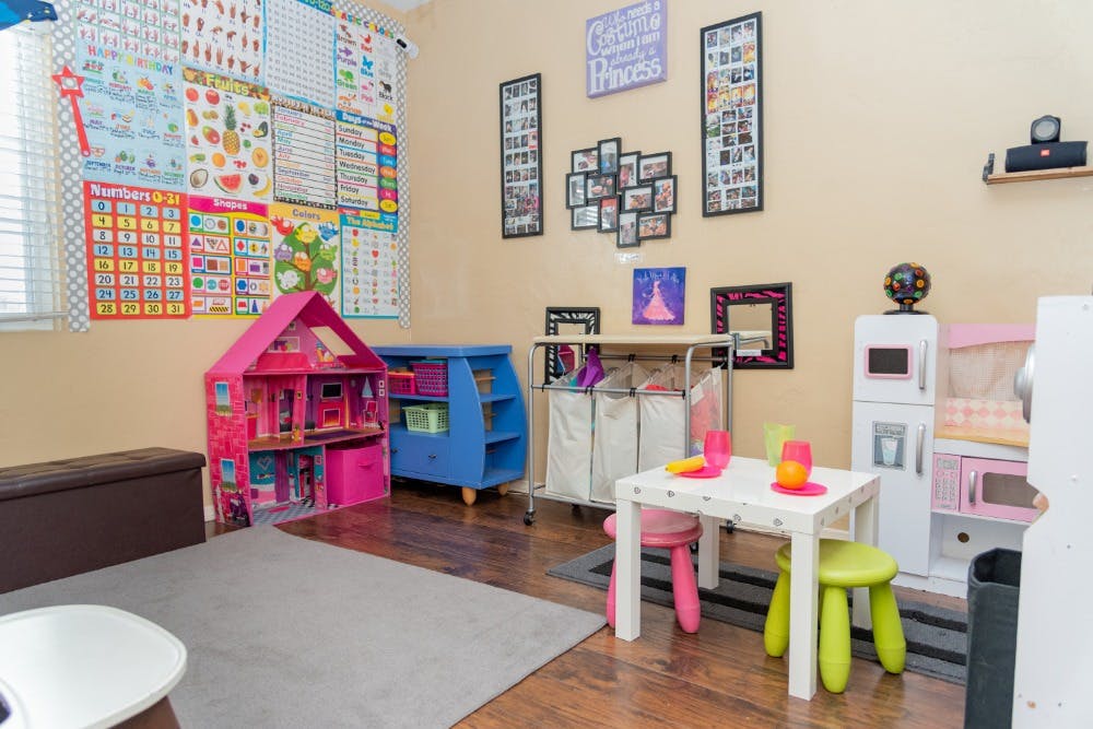 Playroom with a dollhouse, small table and chairs, and toy kitchen