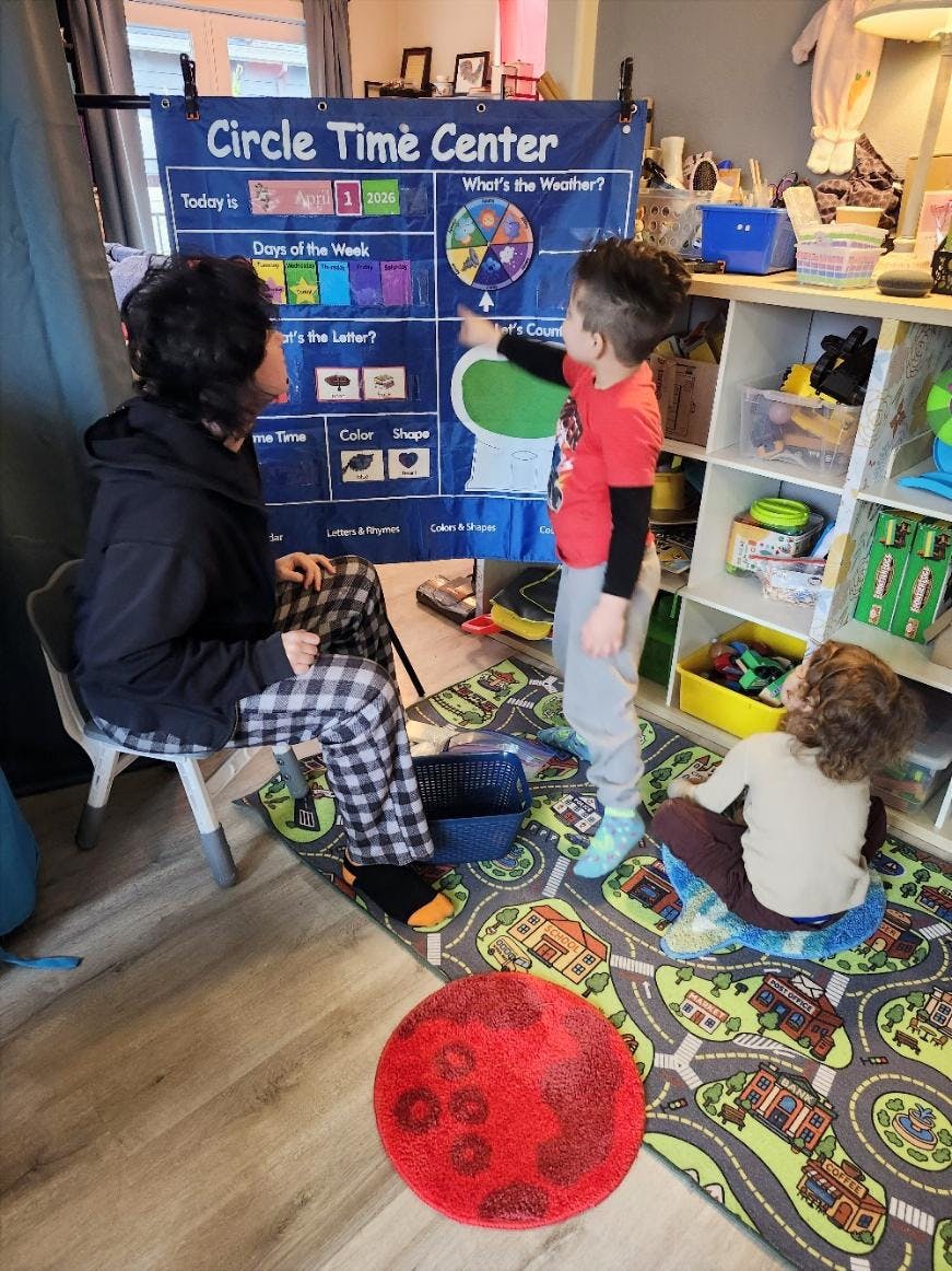 A person and two children in front of a "Circle Time Center" learning chart