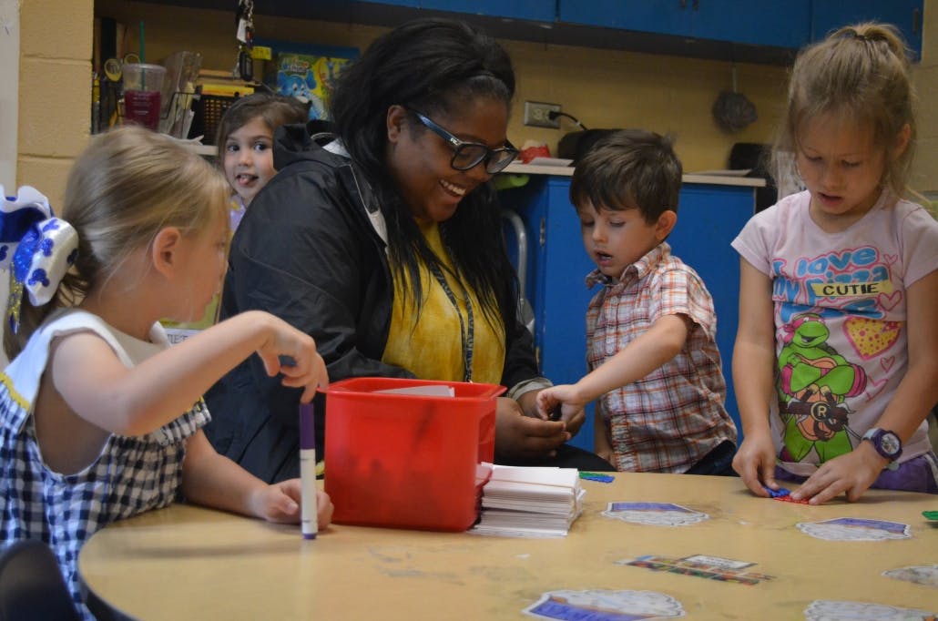 Adult and three children at a table in a classroom