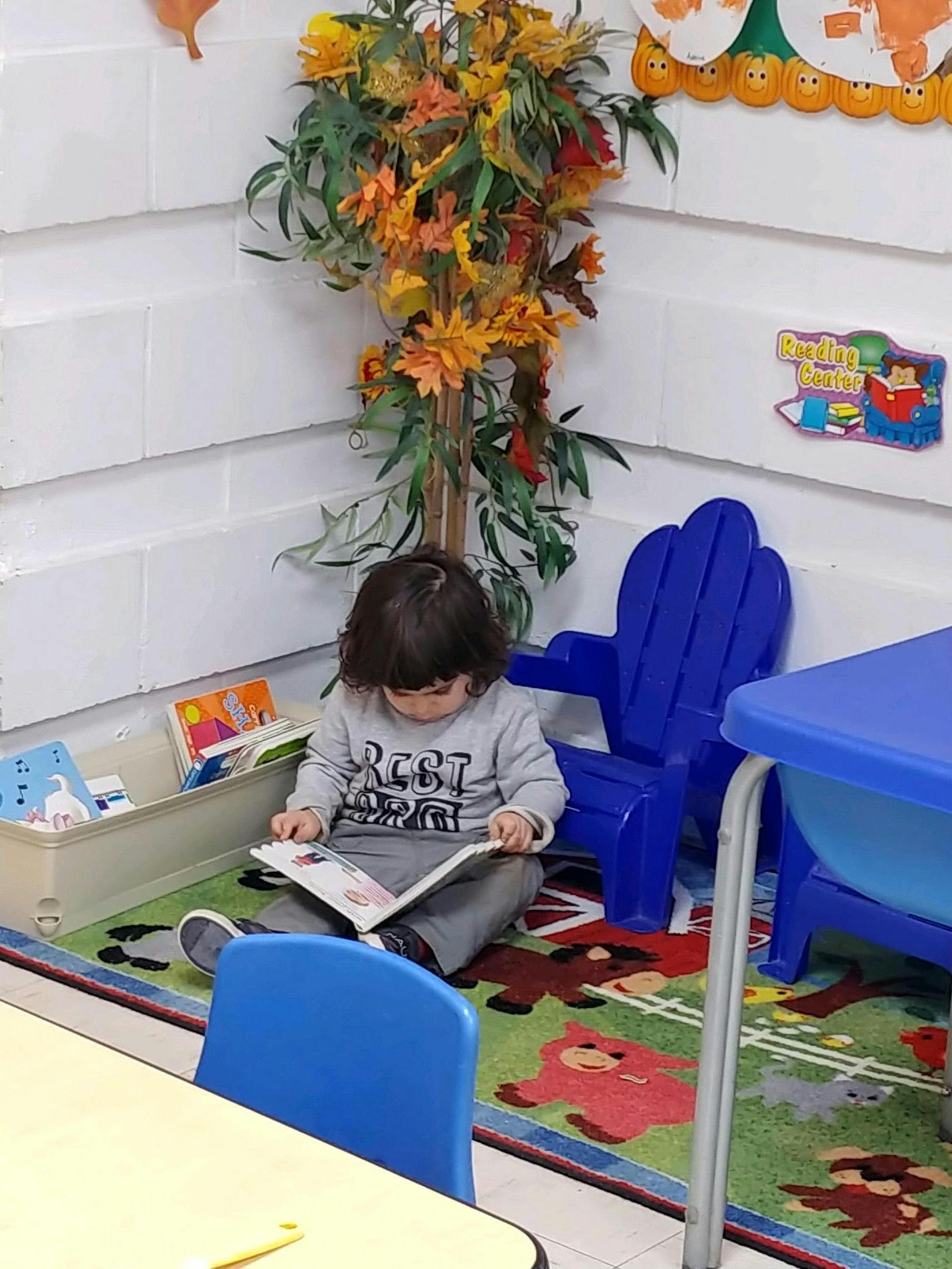 Child sitting on a rug reading a book in a classroom