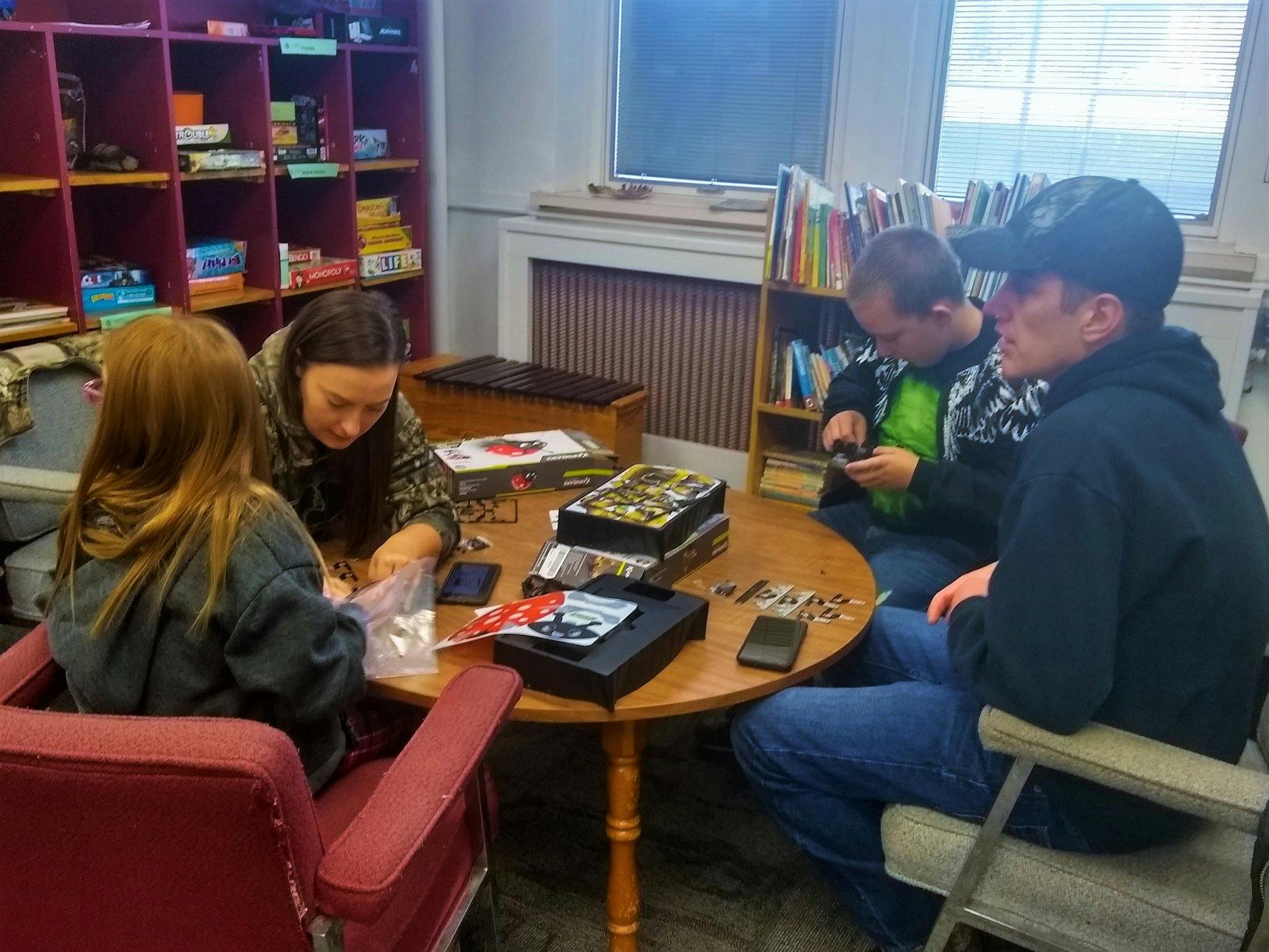 Four people sitting around a table with board games
