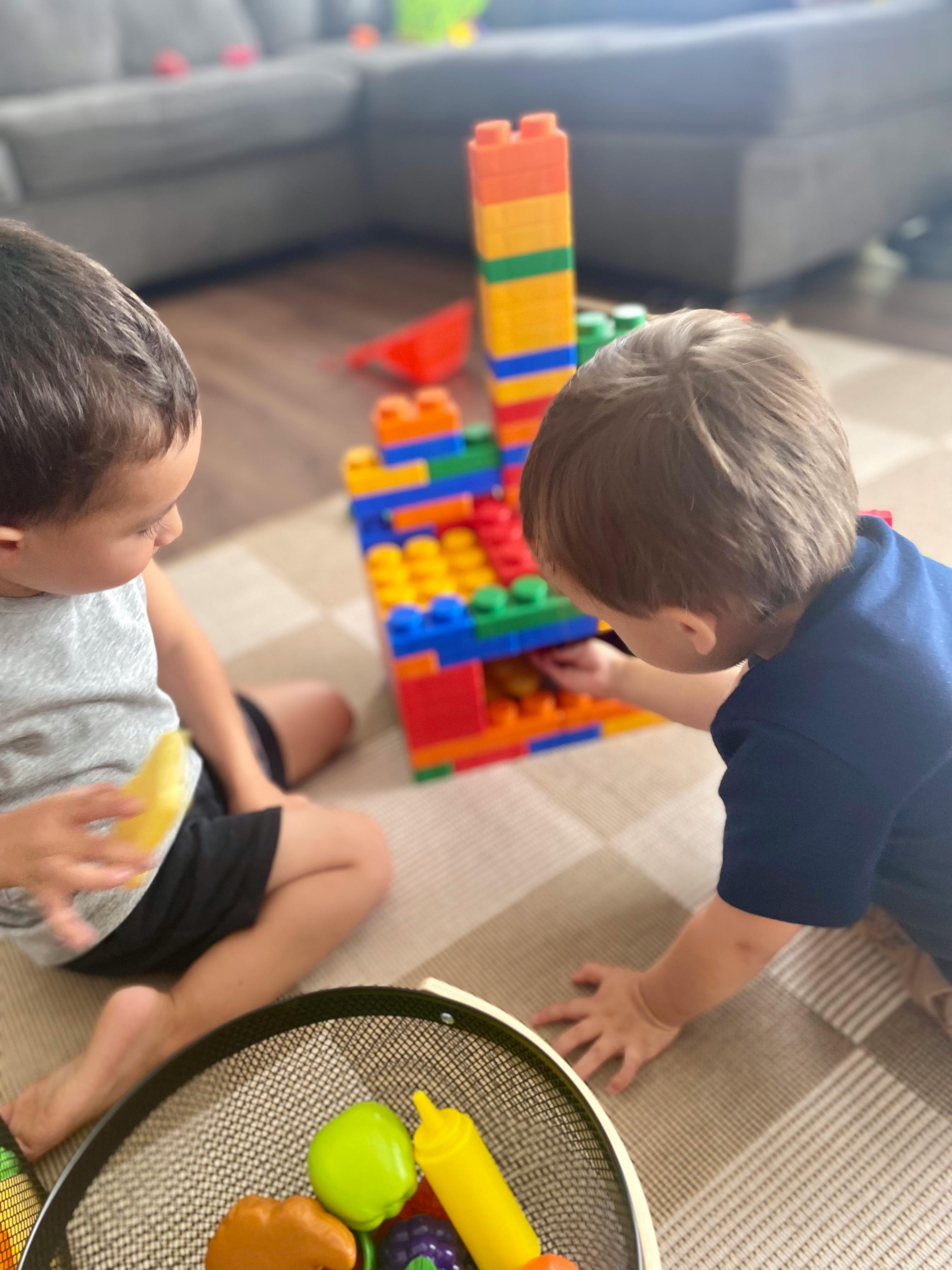 Two children playing with colorful building blocks on the floor