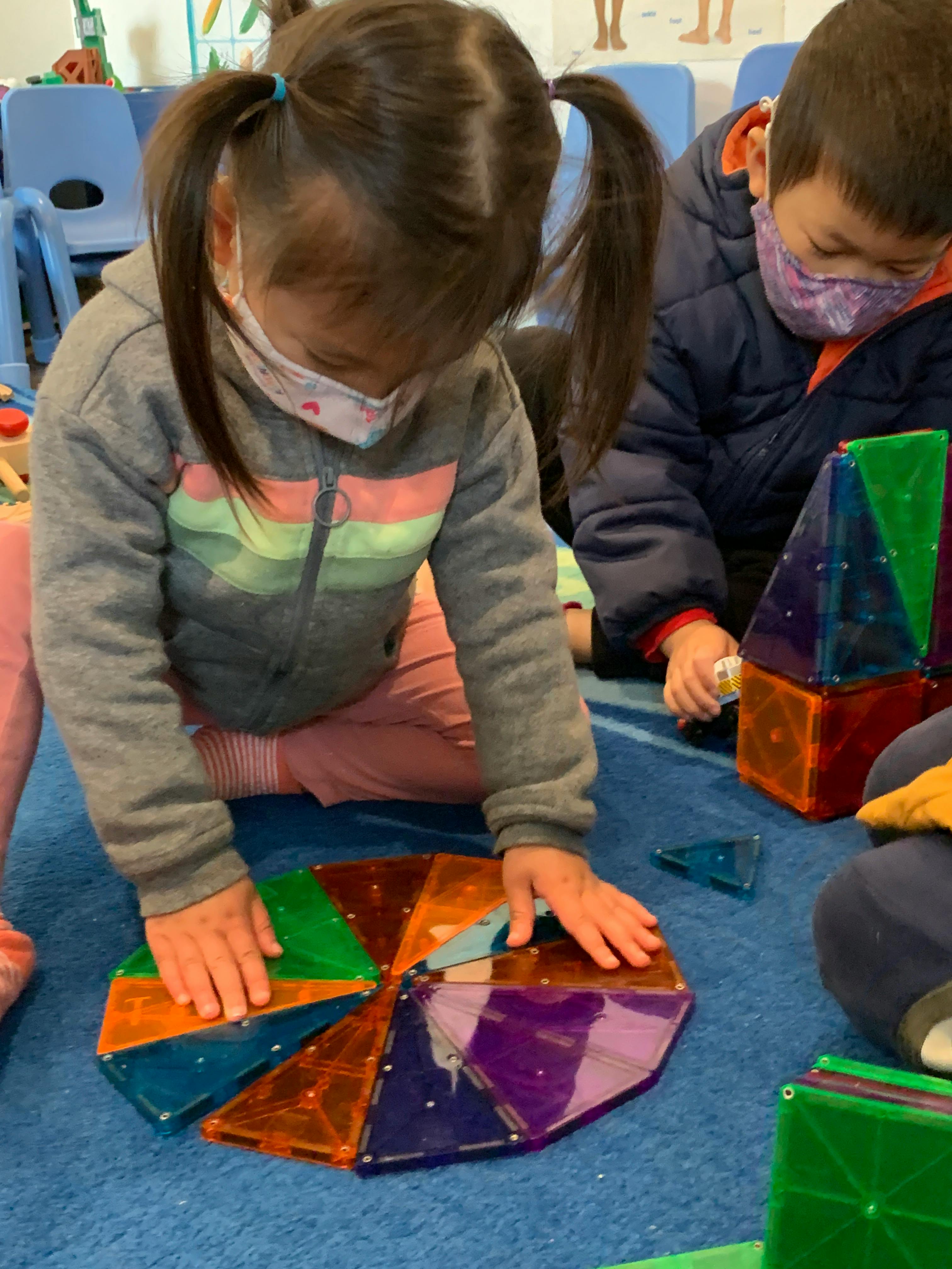 Child playing with colorful magnetic tiles on the floor