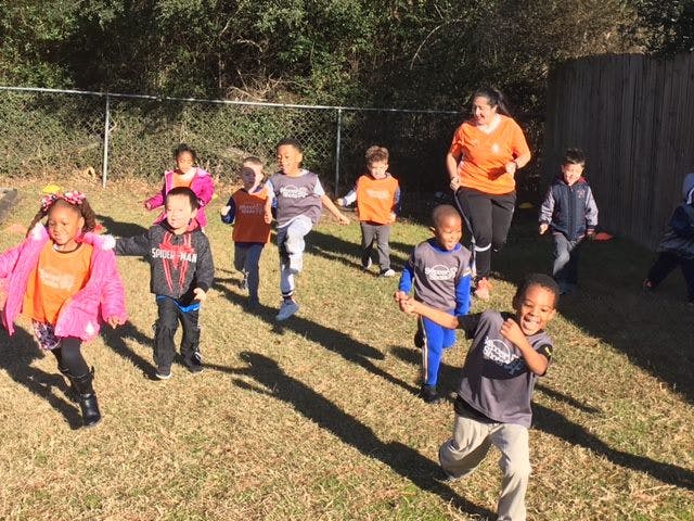 Adult and children running on grass
