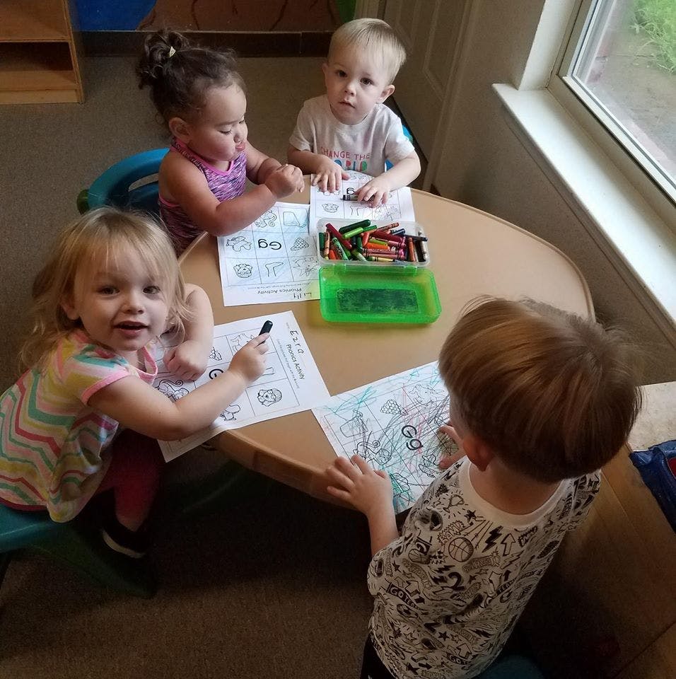 Four children coloring at a table with crayons