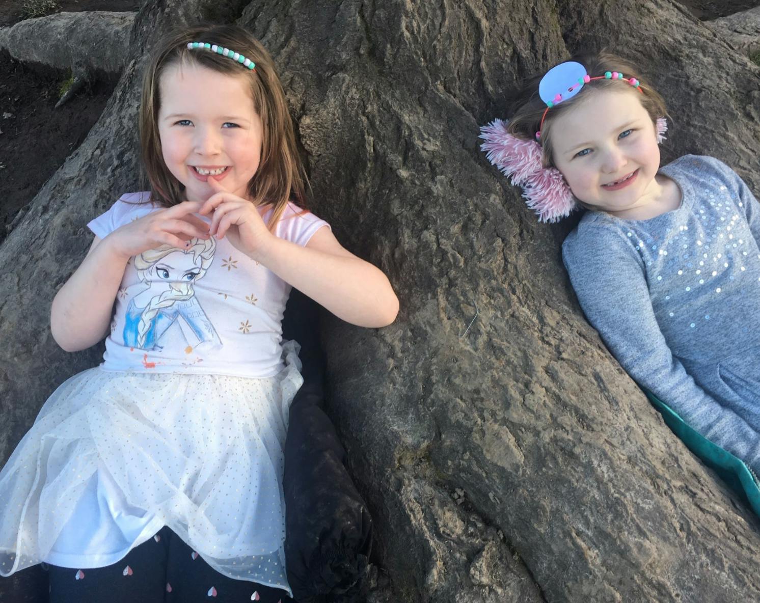 Two children sitting on tree roots