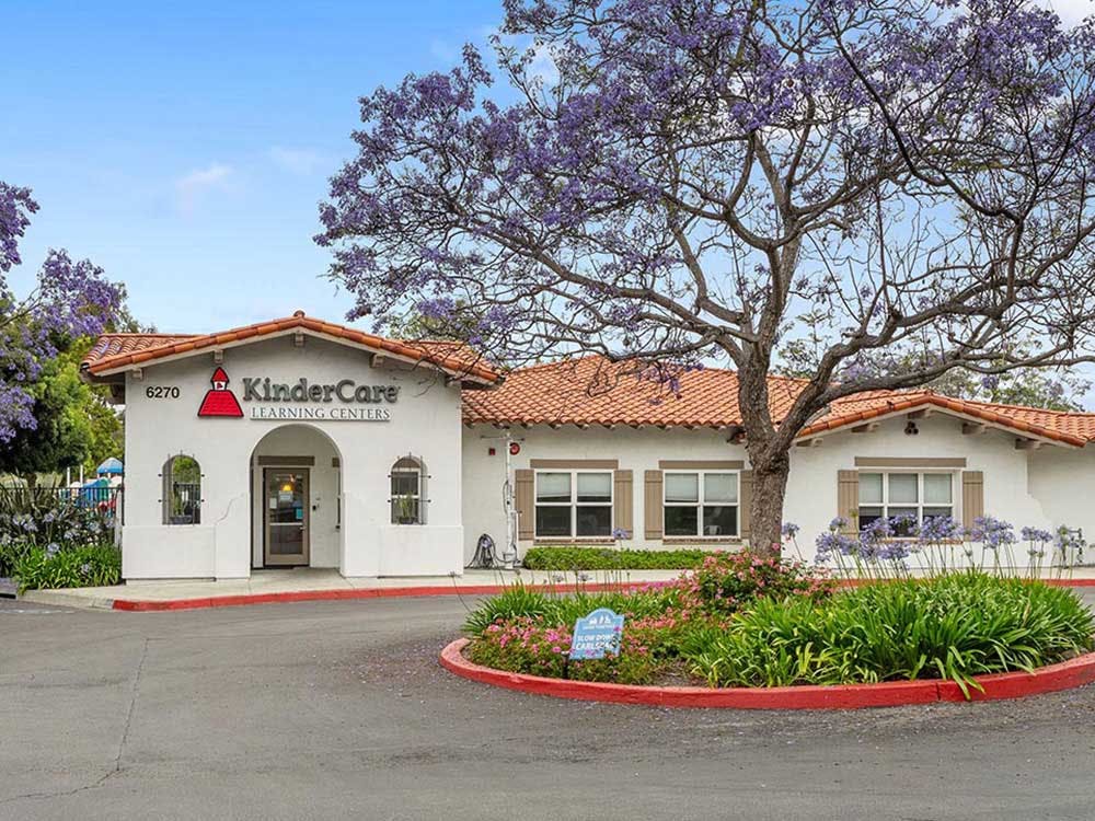 KinderCare Learning Centers building exterior with a purple-flowered tree