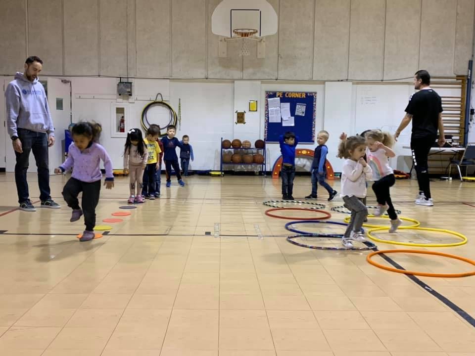 Children and adults in a gym with hula hoops
