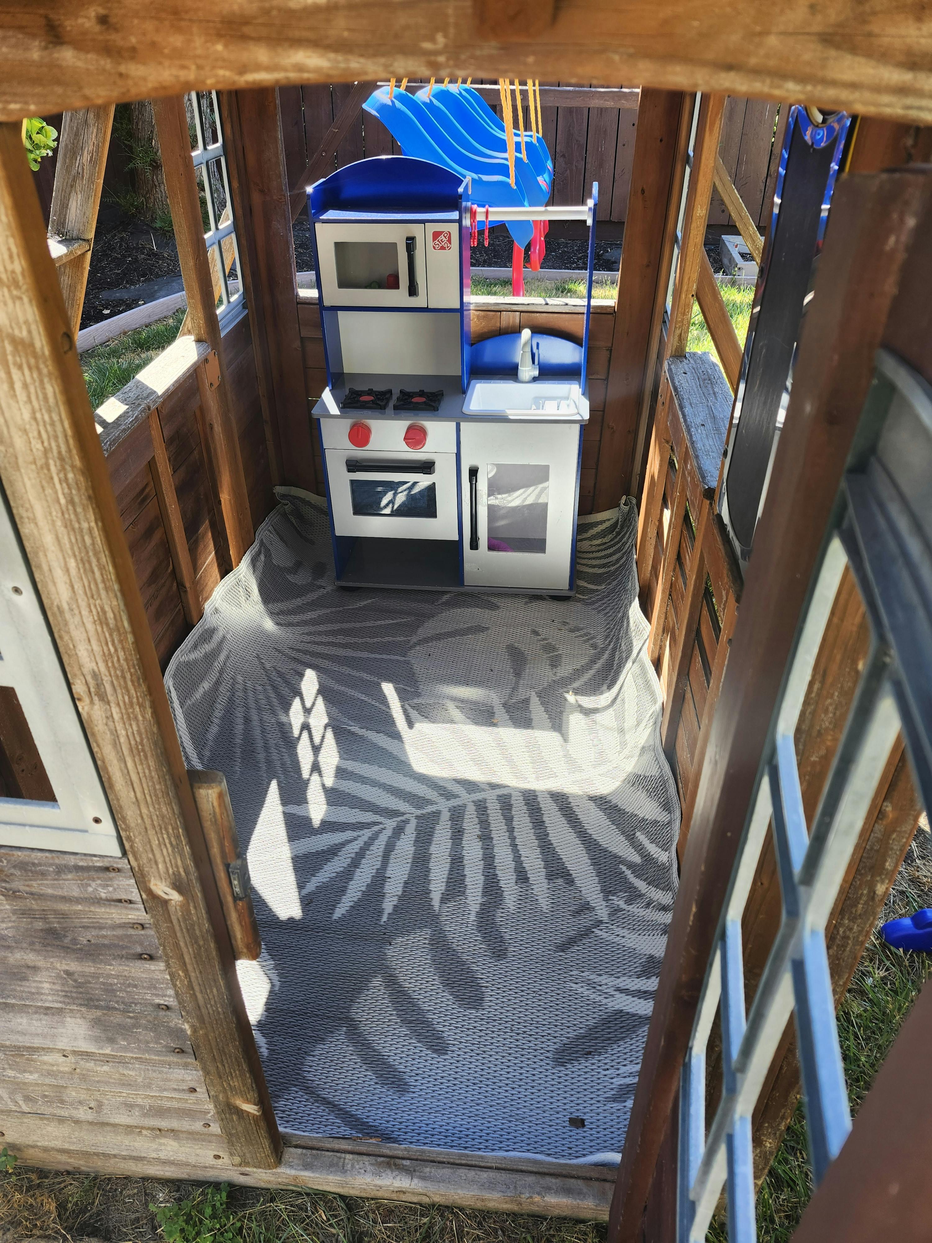 Toy kitchen set inside a wooden playhouse