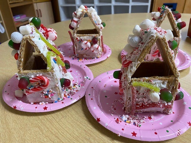 Gingerbread houses decorated with candy and icing on pink plates