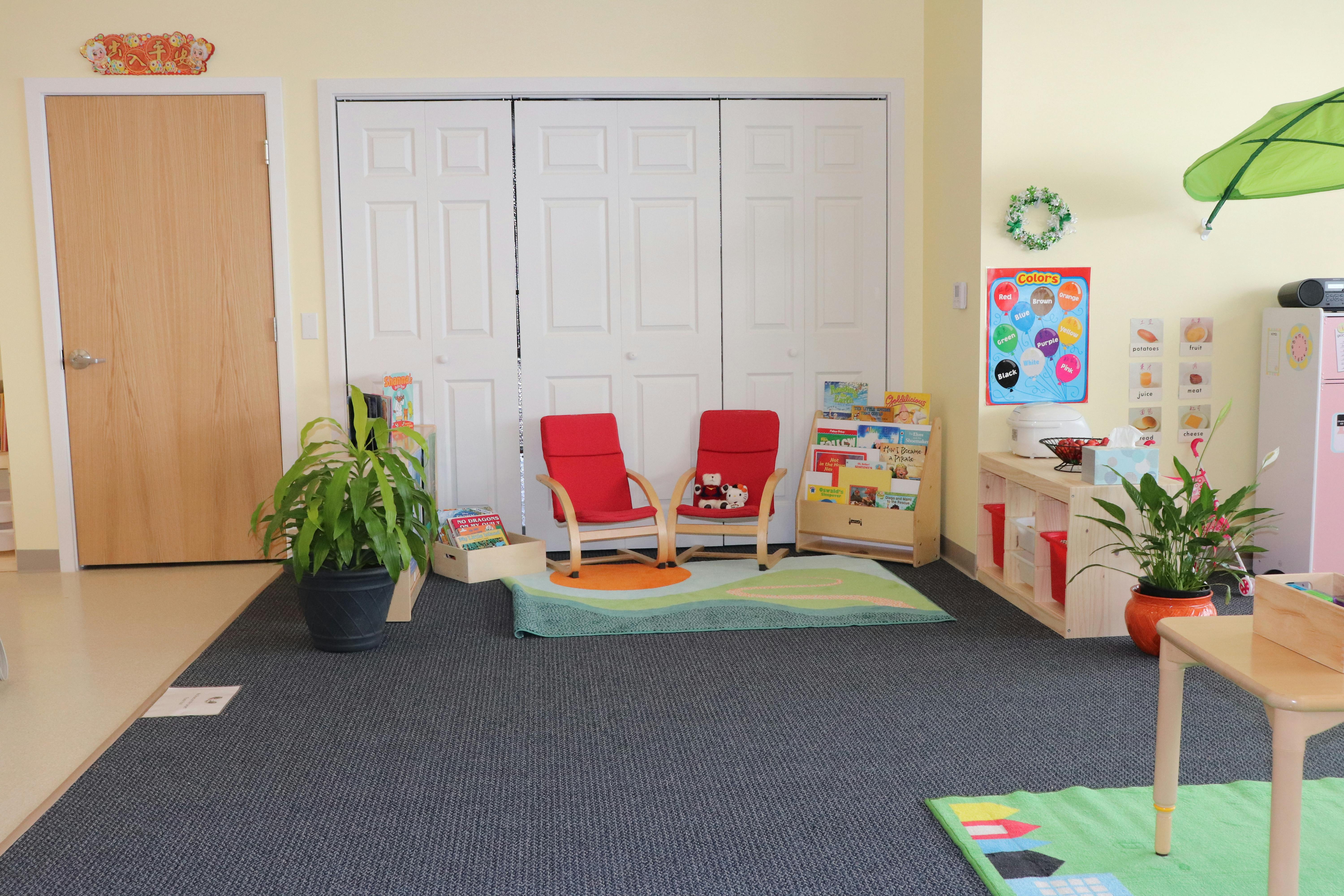 Two red chairs on a rug in a room with a wooden door and white closet doors