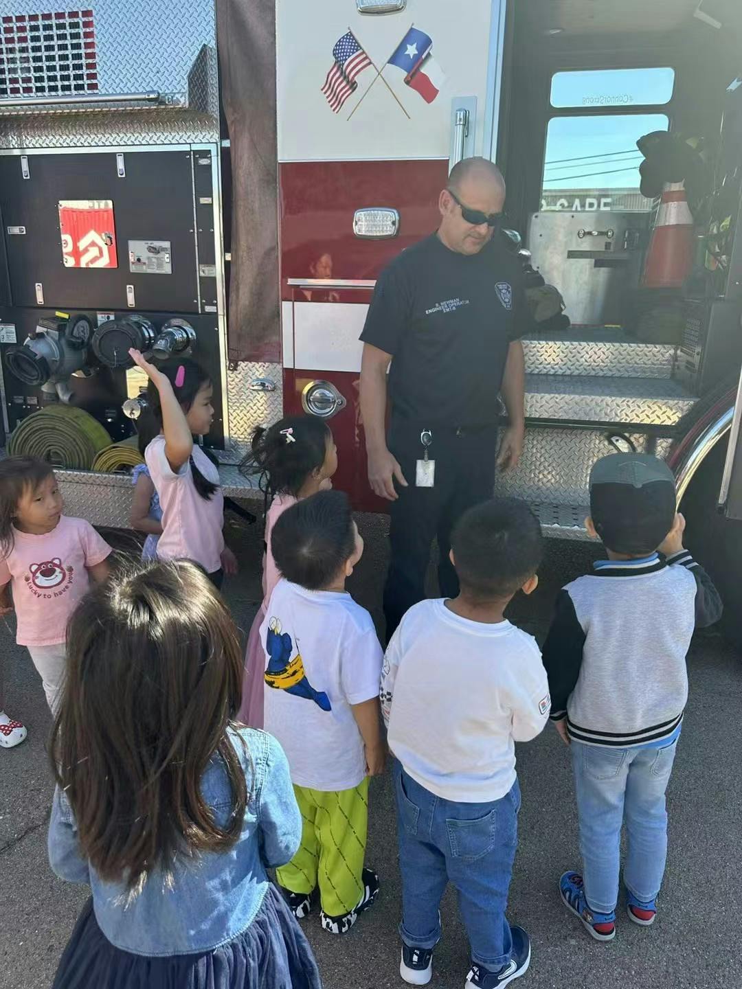 Firefighter in sunglasses talking to a group of children near a fire truck