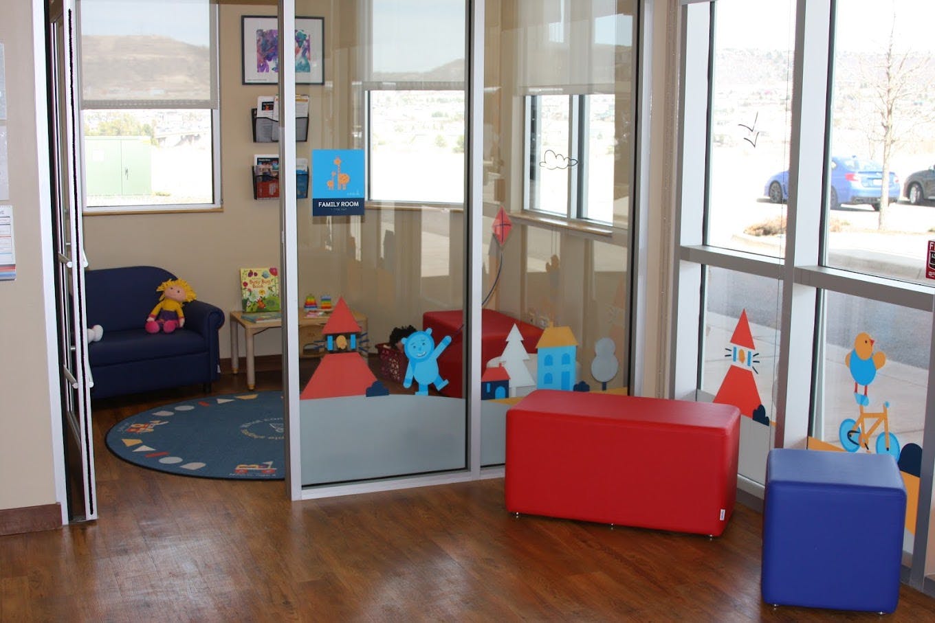 Family room with a blue couch, small table, and a glass partition with cartoon stickers