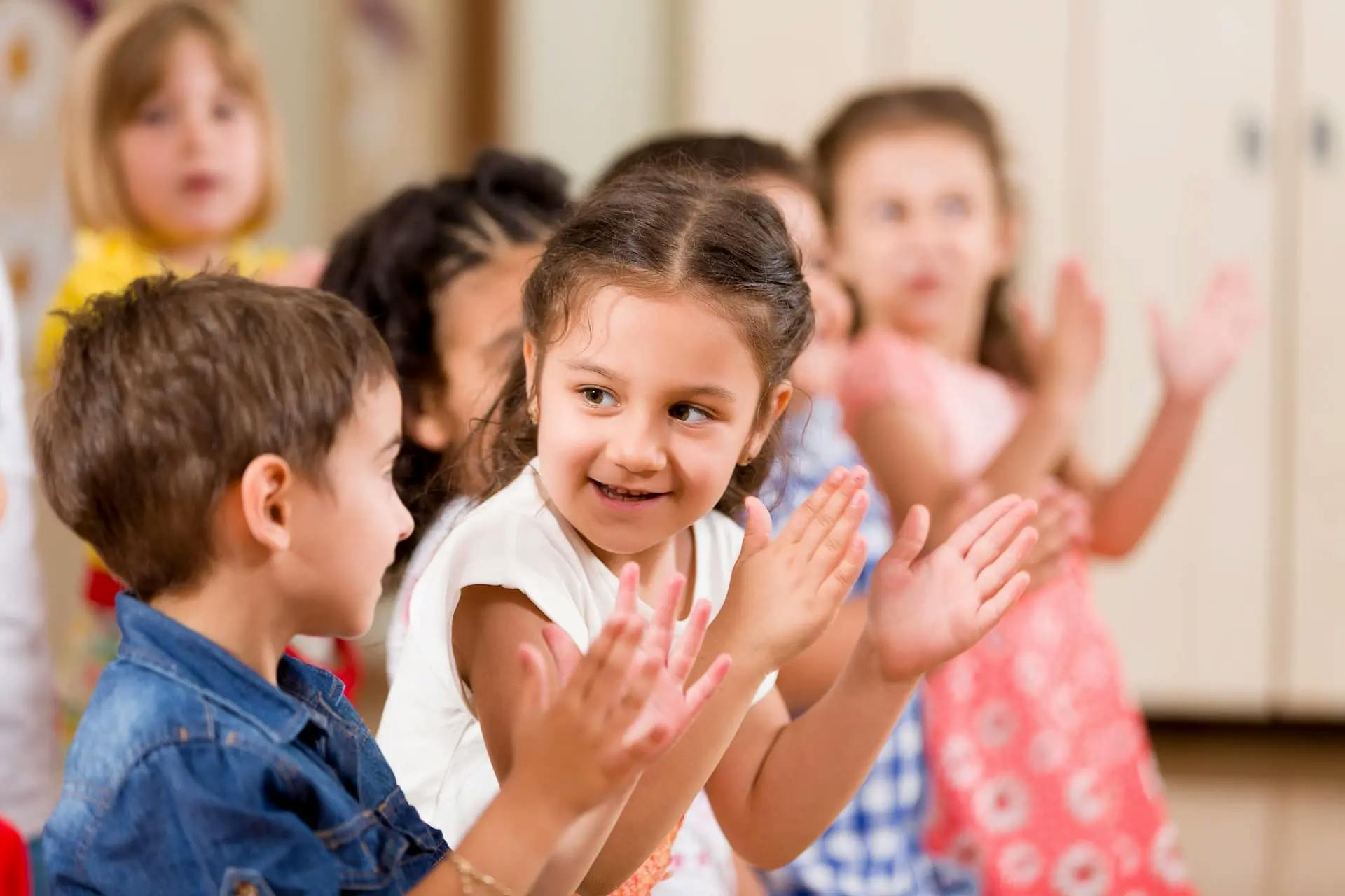Group of children clapping in a classroom