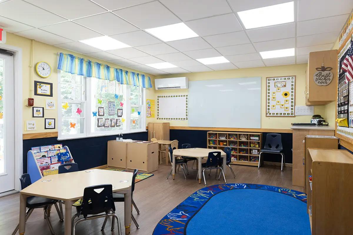 Empty classroom with small tables, chairs, and learning materials