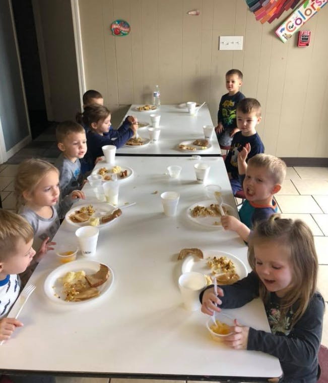 Children eating at tables in a classroom