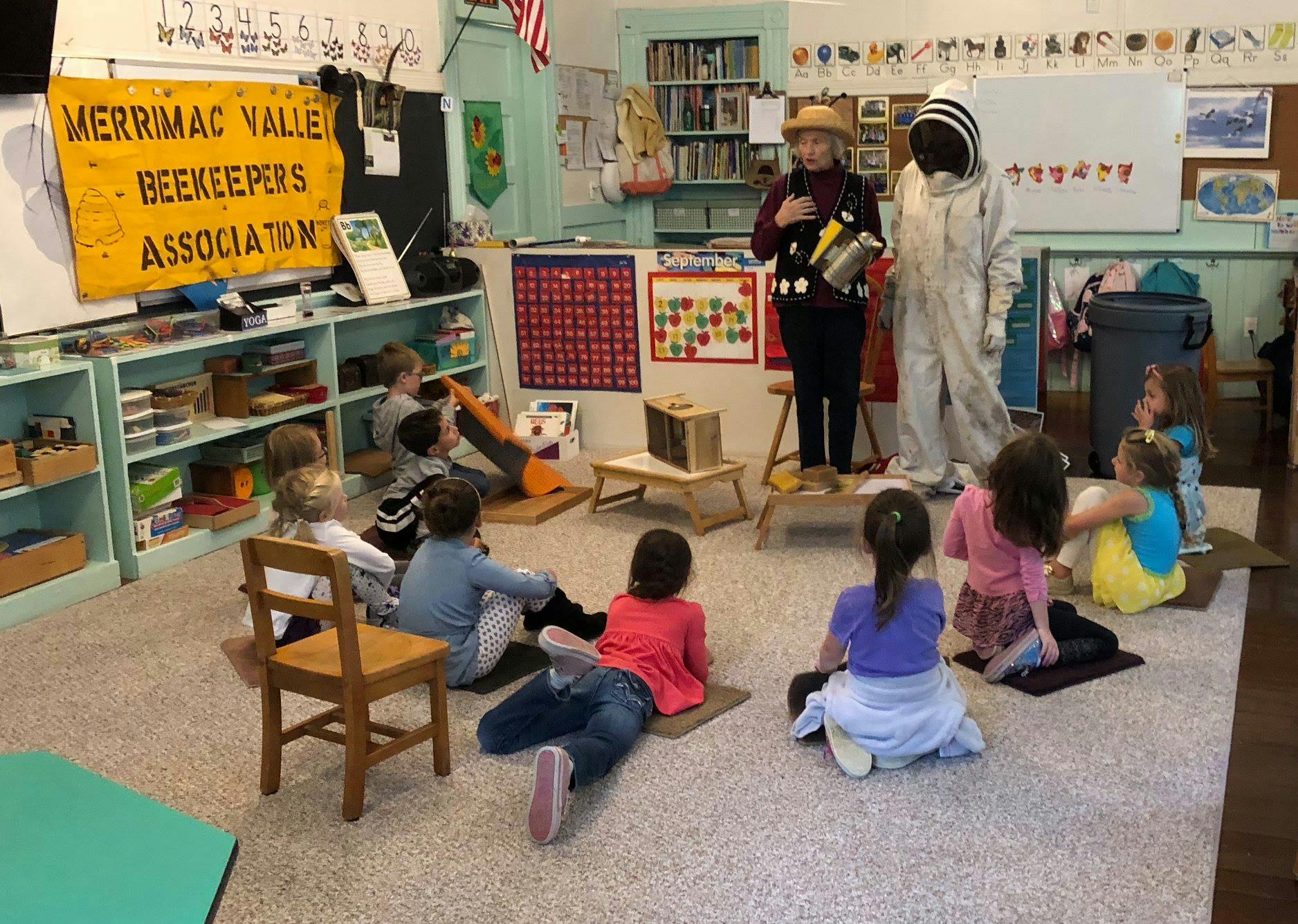Adults in bee-themed costumes presenting to children in a classroom