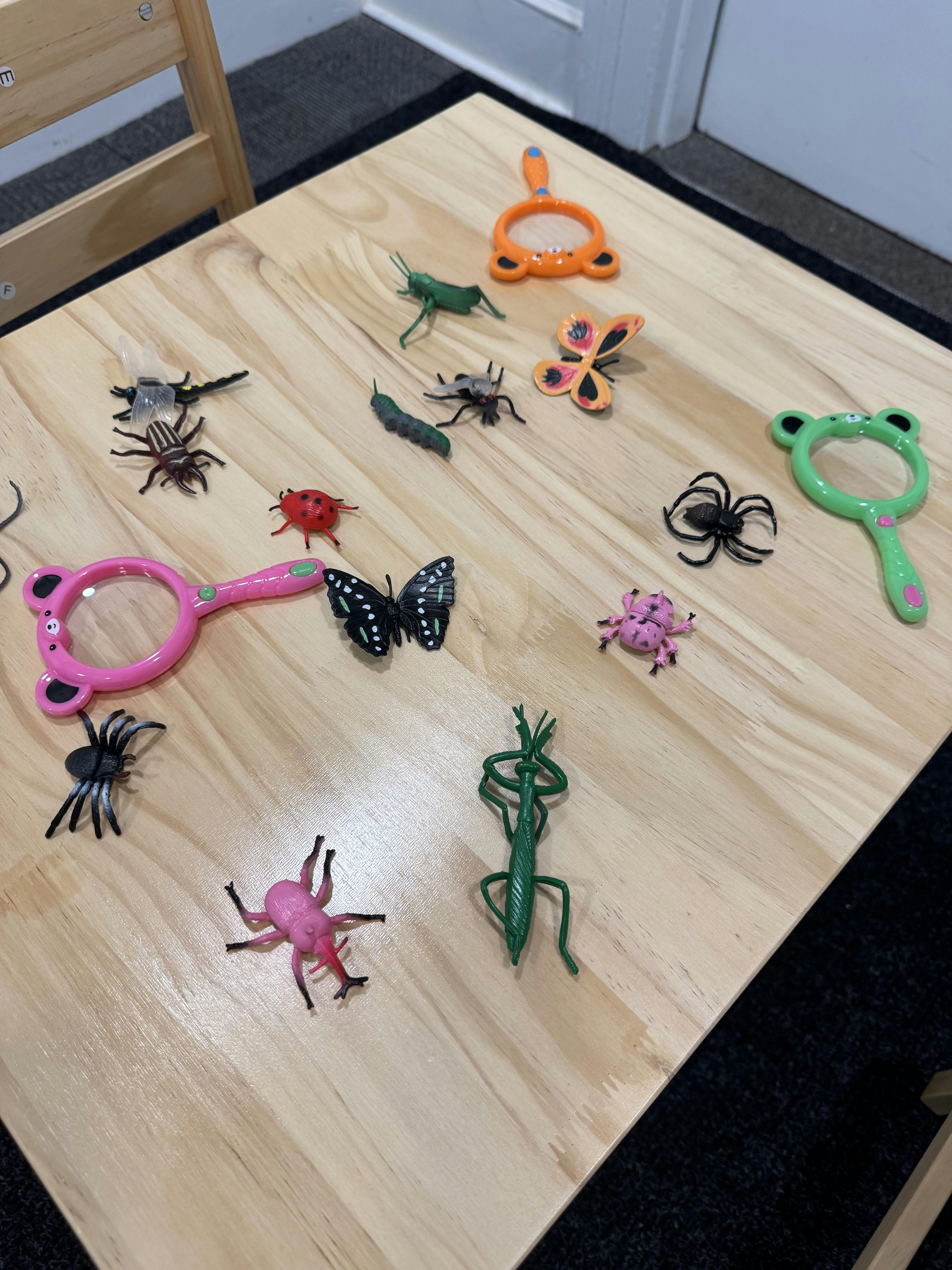 Plastic toy insects and magnifying glasses on a light wooden table