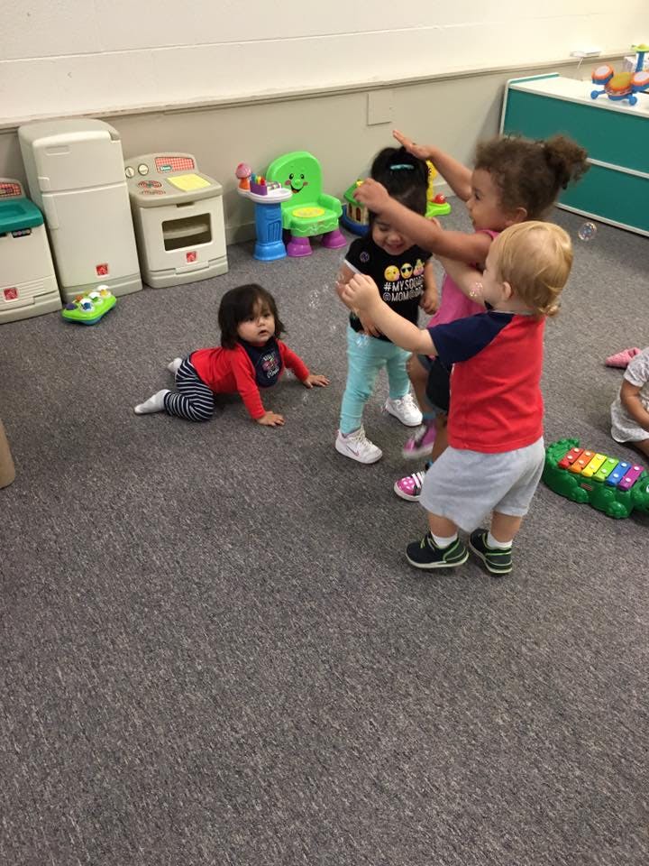 Three children playing together, one child crawling