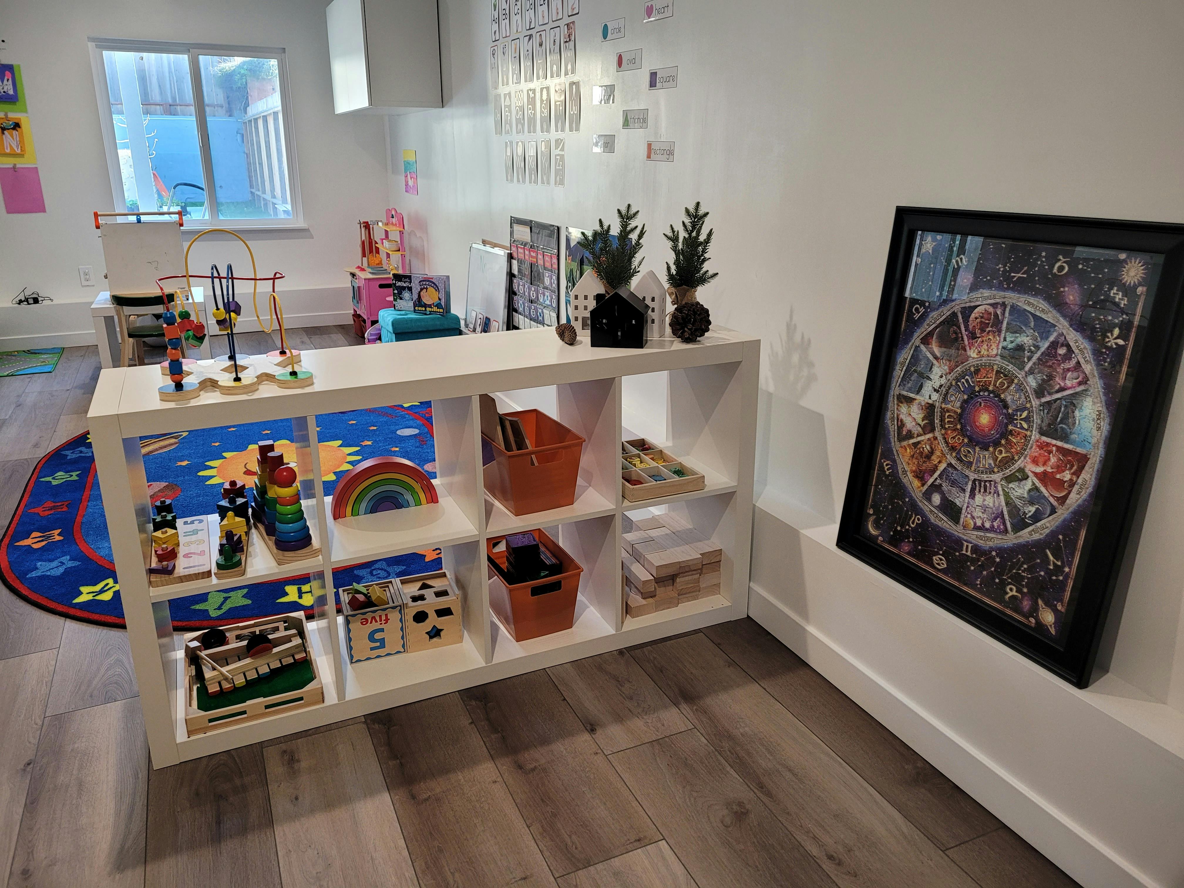 White shelving unit with toys and a framed picture on a wall