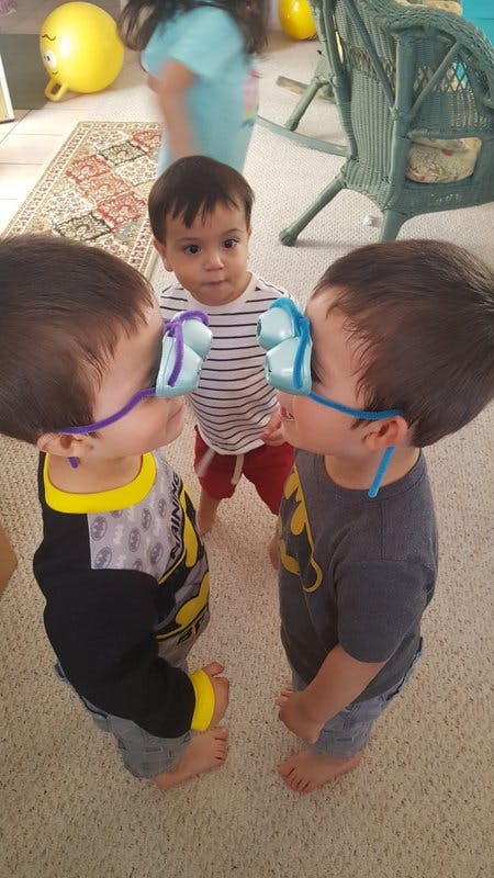 Two children wearing novelty glasses with a third child standing between them