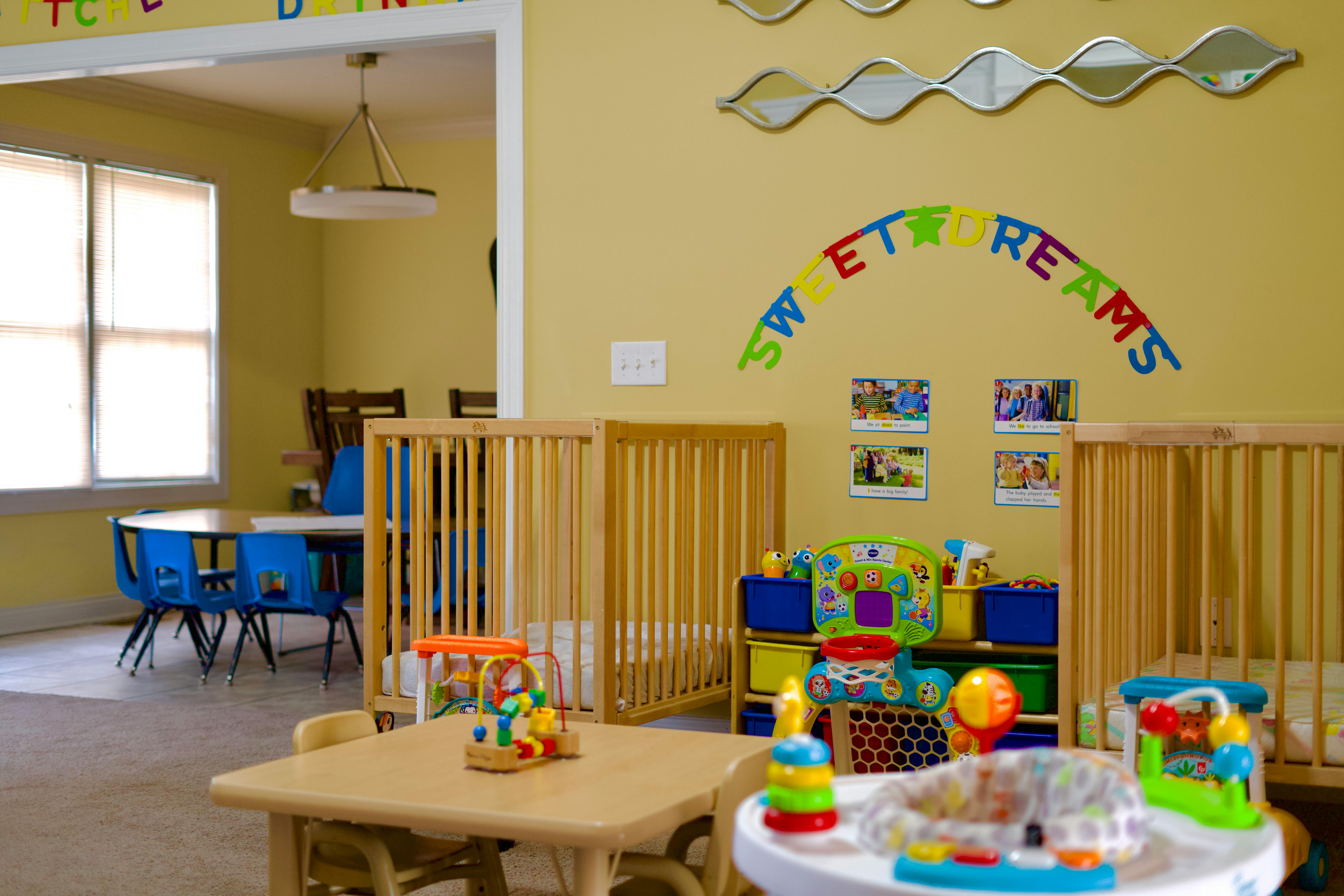 Daycare room with cribs, small tables, and toys