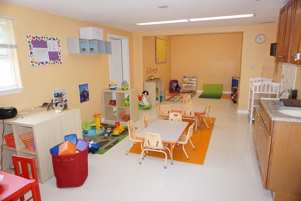 Playroom with small tables and chairs, toys, and a kitchen area