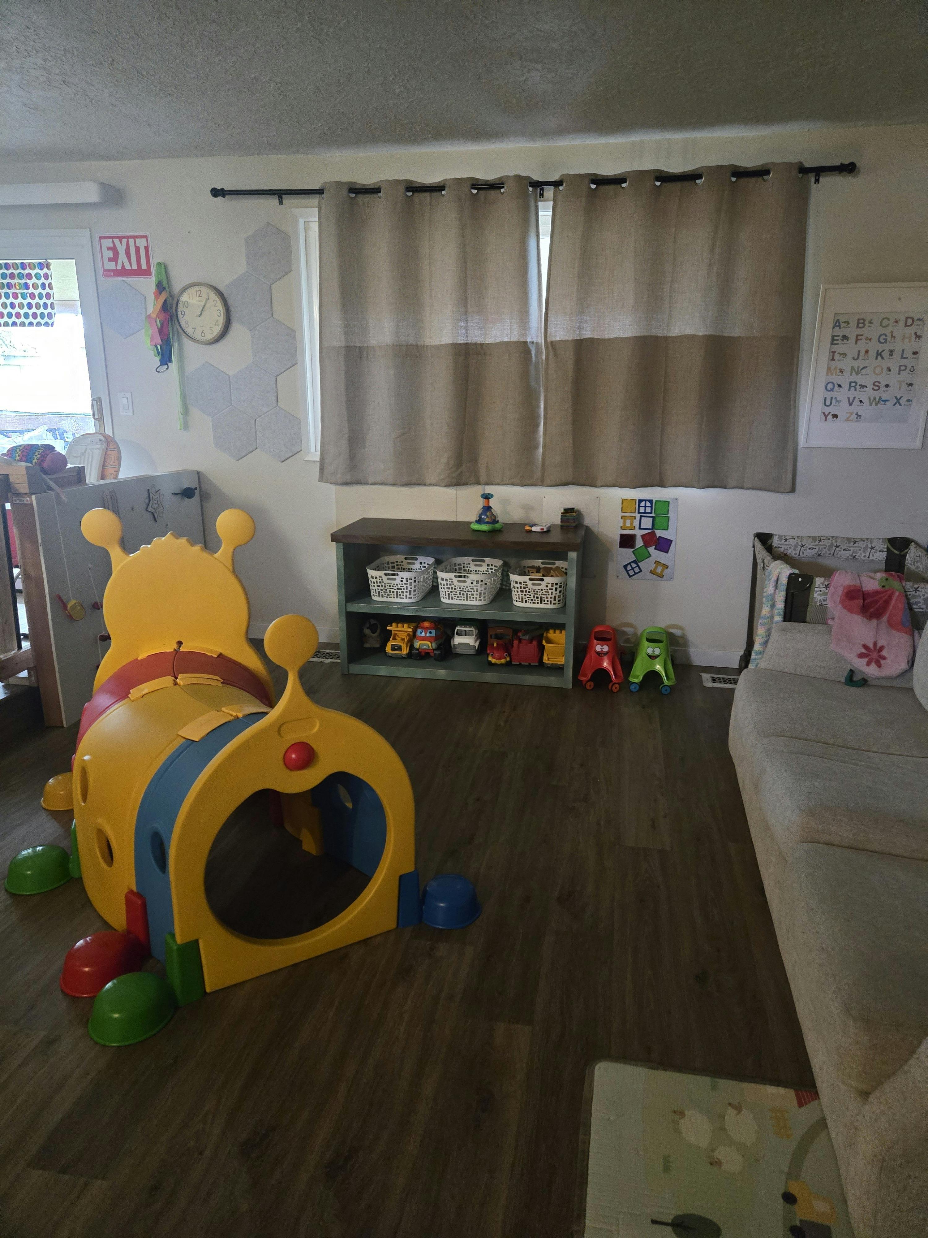 Child's play area with a colorful tunnel, toy storage, and a couch
