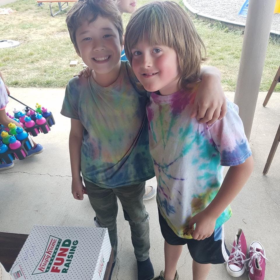 Two children in tie-dye shirts with arms around each other