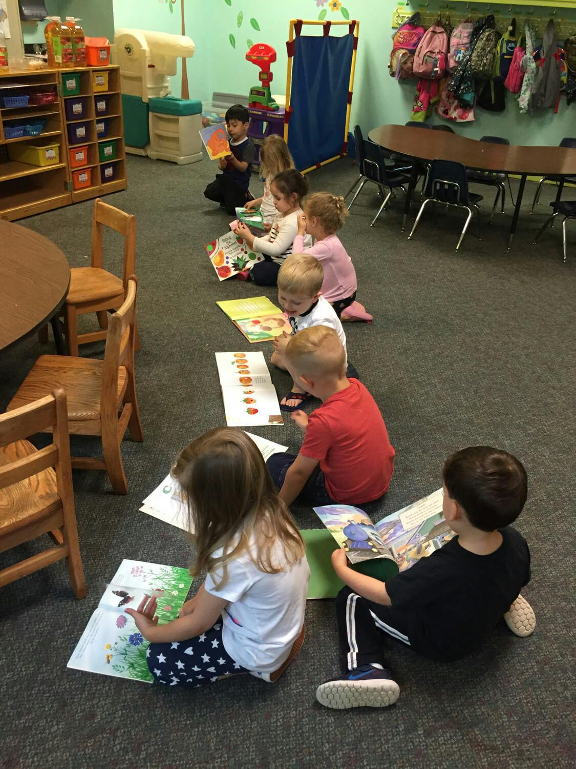 Children sitting on the floor reading books in a classroom
