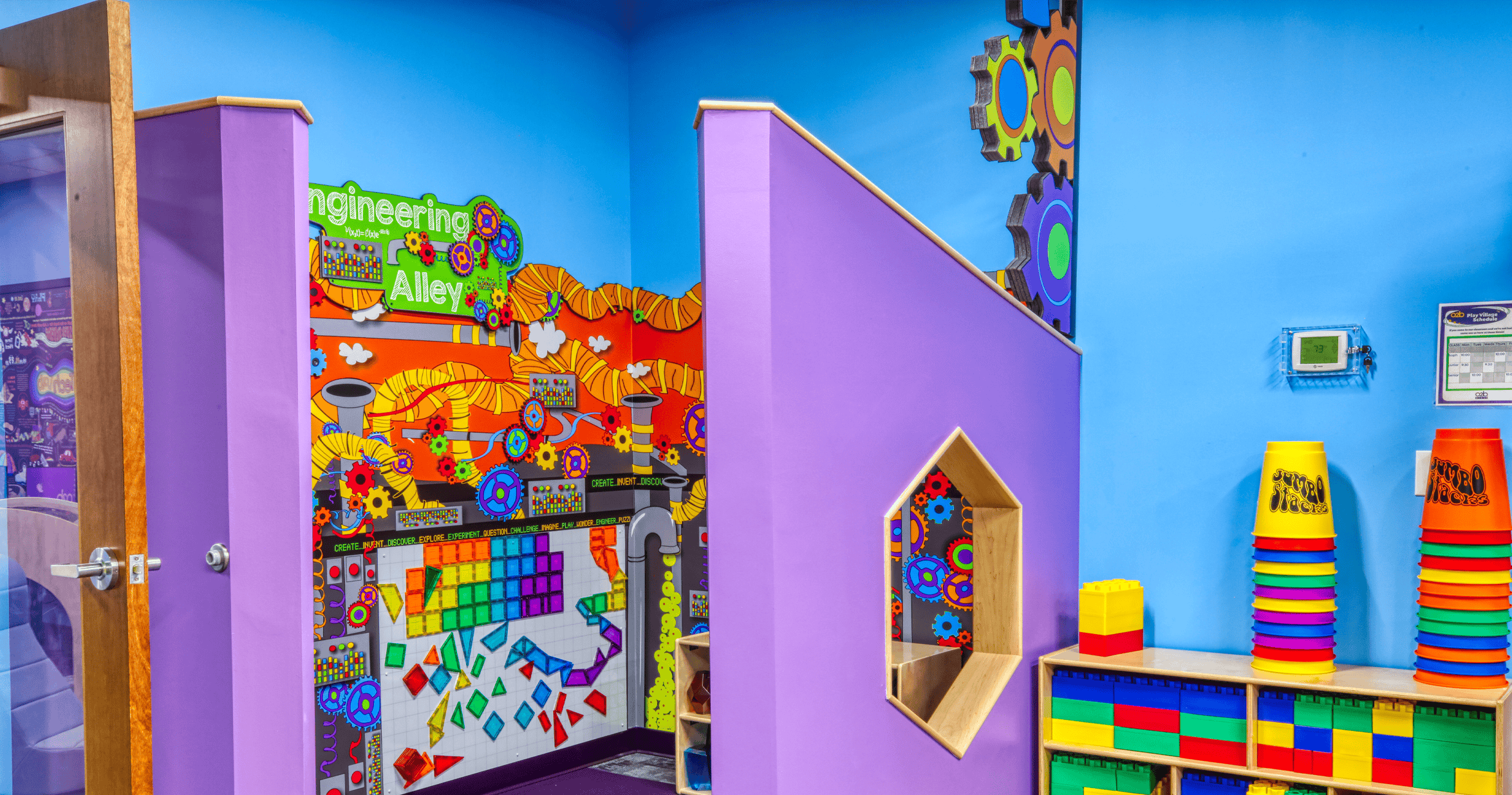 An indoor play area with Engineering Alley written on a colorful wall mural
