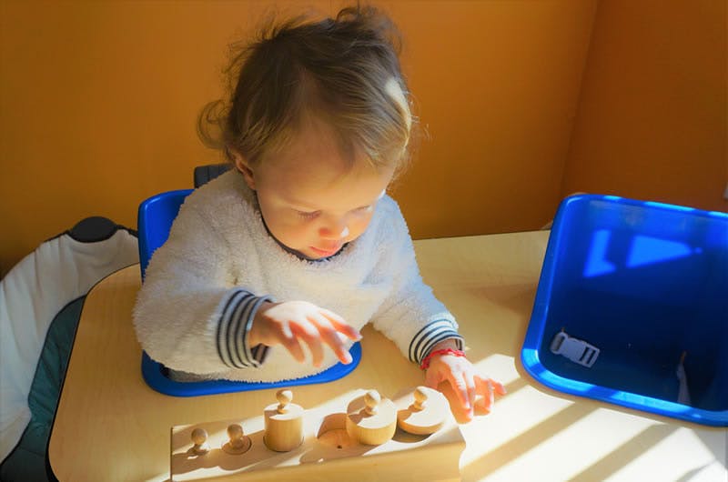 Child in a high chair playing with wooden toys