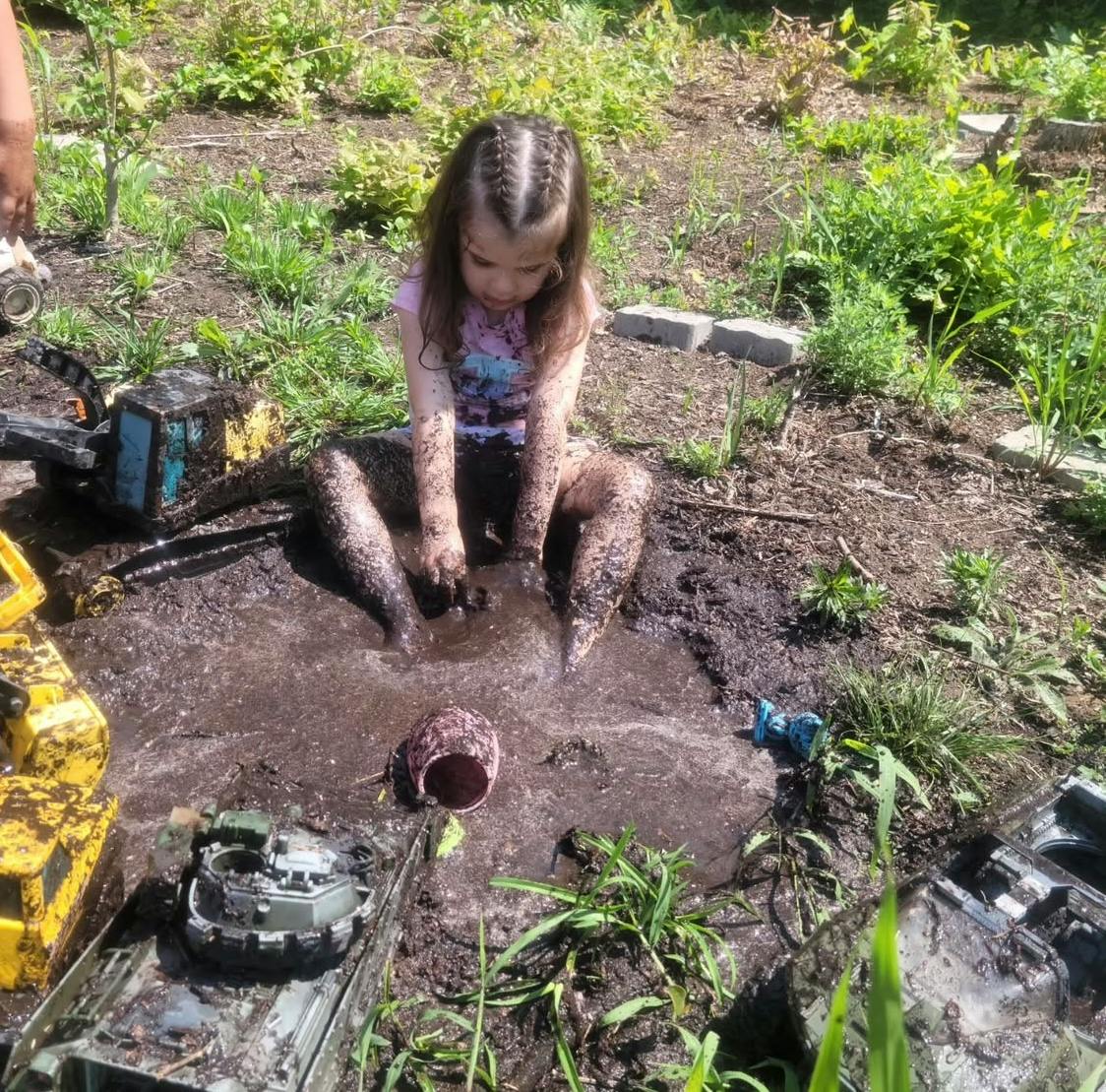 Child sitting in mud playing with hands